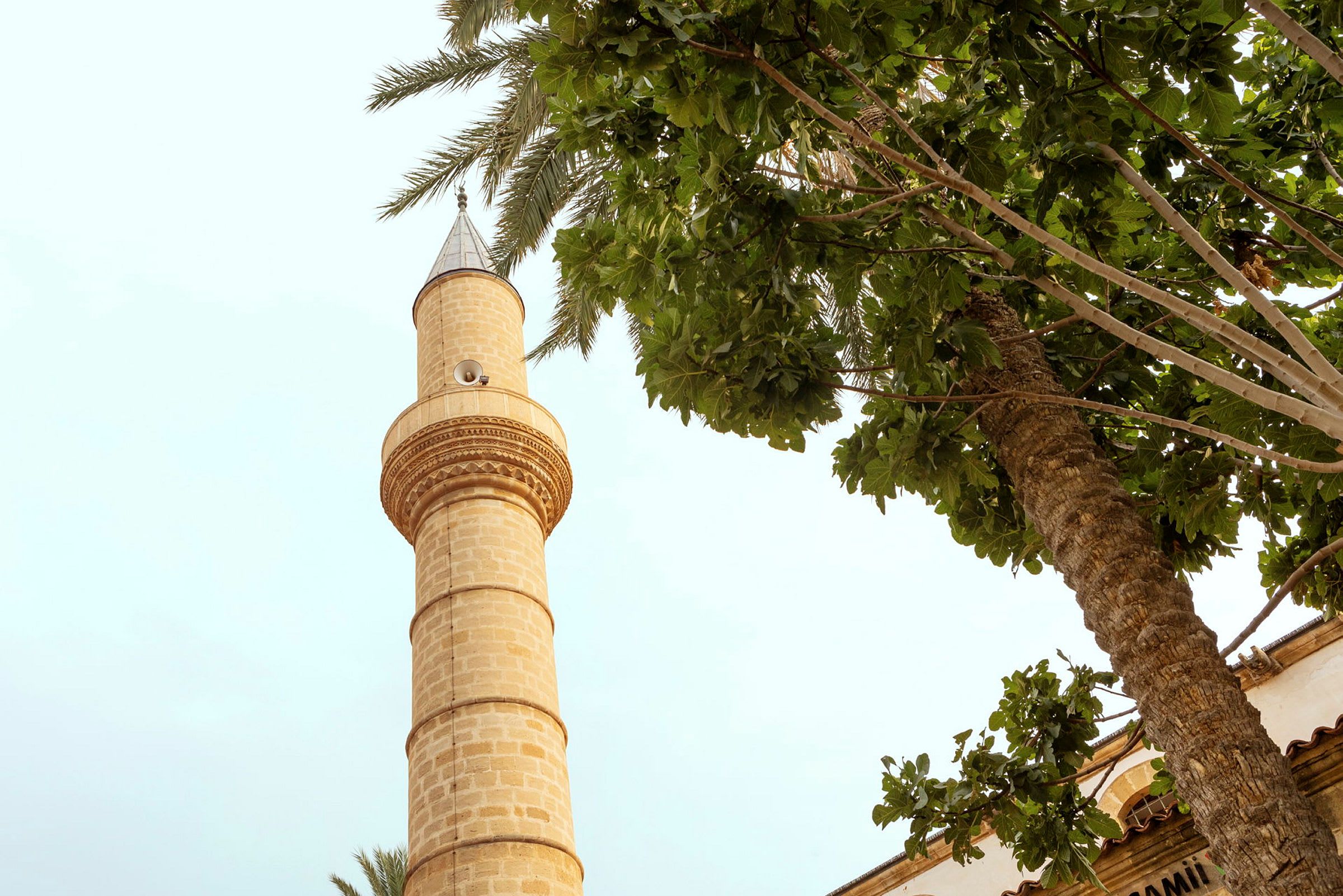 En minaret vid sidan av trädtoppar. (AI-genererad text)
