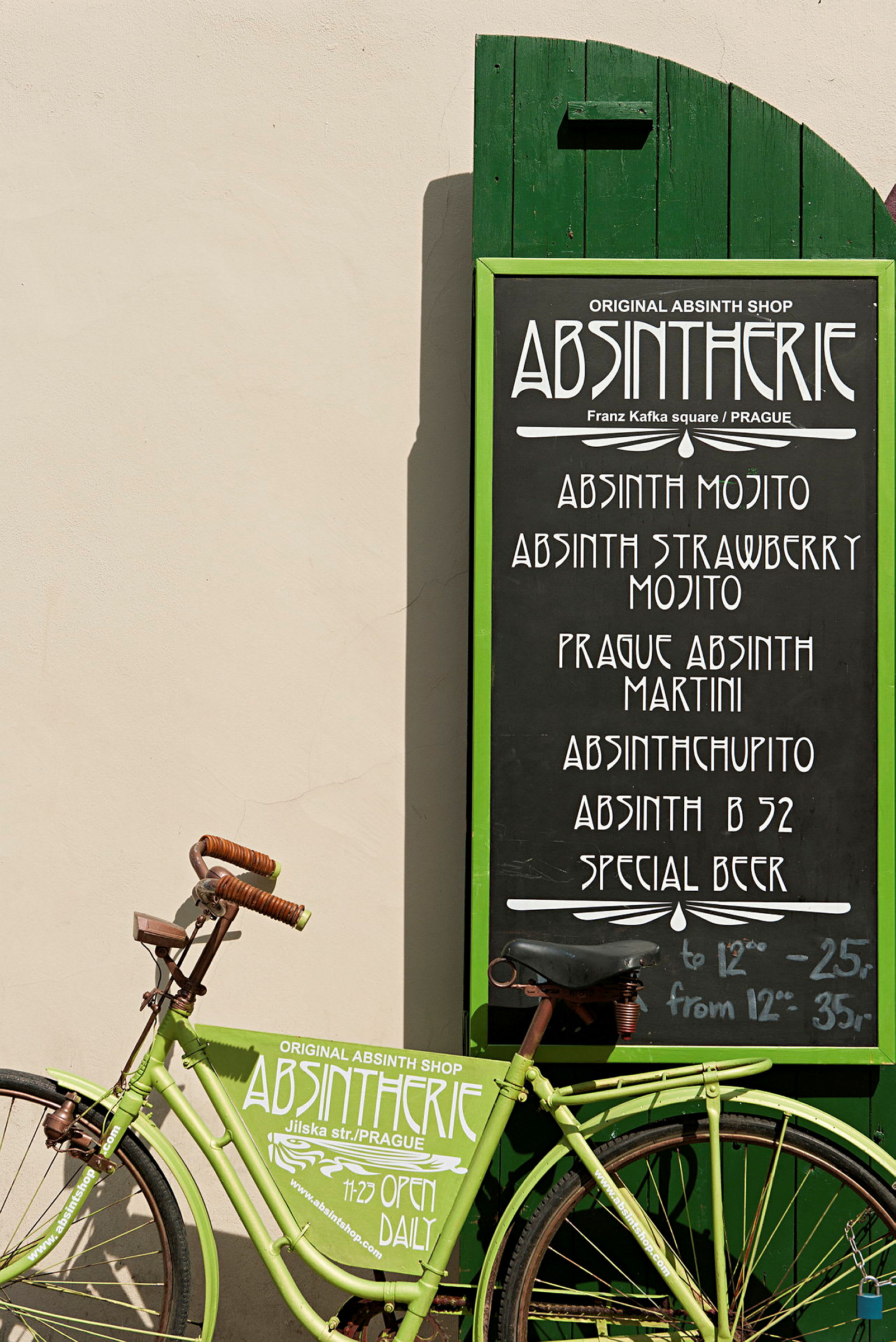 En grön cykel framför en grön skylt som visar en meny för en absint-shop. (AI-genererad text)