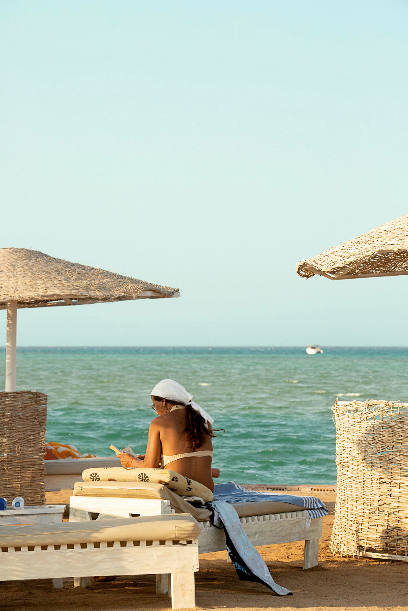 Person sitter i solstol på stranden med utsikt över havet. (AI-genererad text)