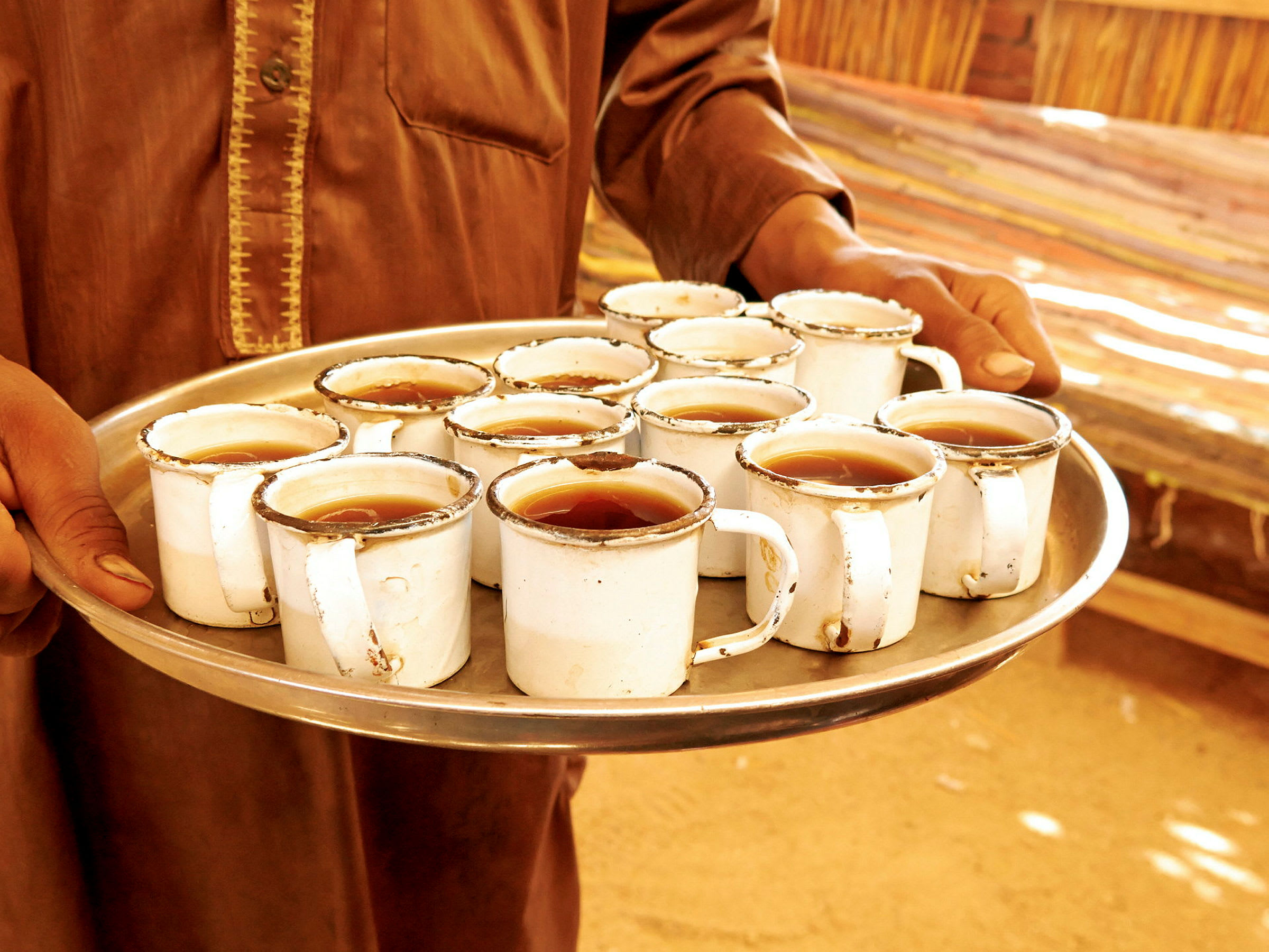 En person håller en bricka med koppar fyllda med te. (AI-genererad text)