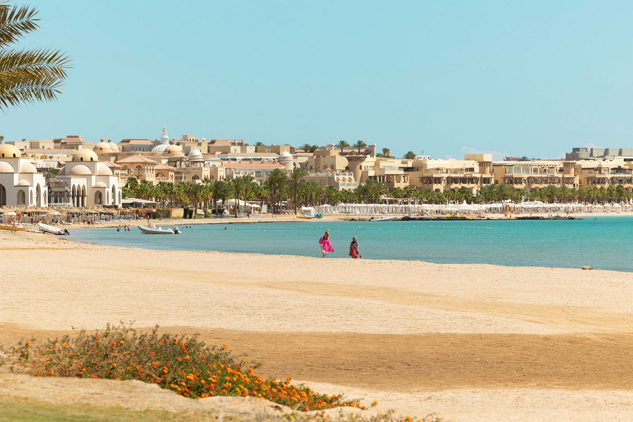Strand med byggnader och palmer i bakgrunden. (AI-genererad text)