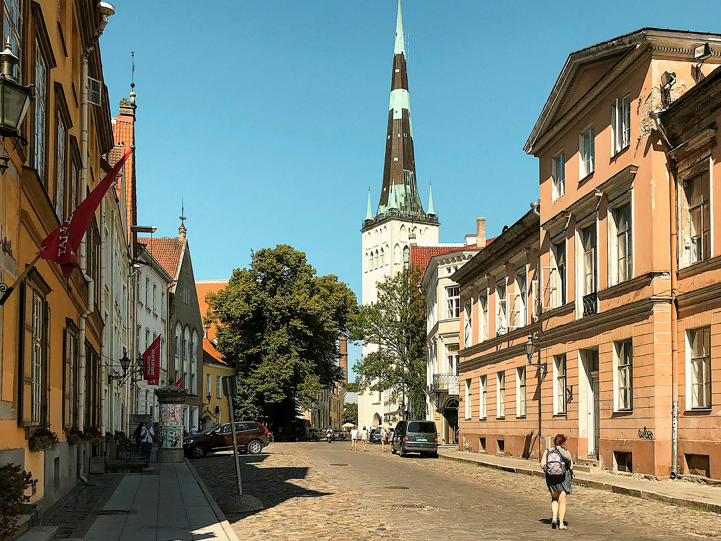 En stadsgata kantad av gamla byggnader med en kyrktorn i bakgrunden. (AI-genererad text)