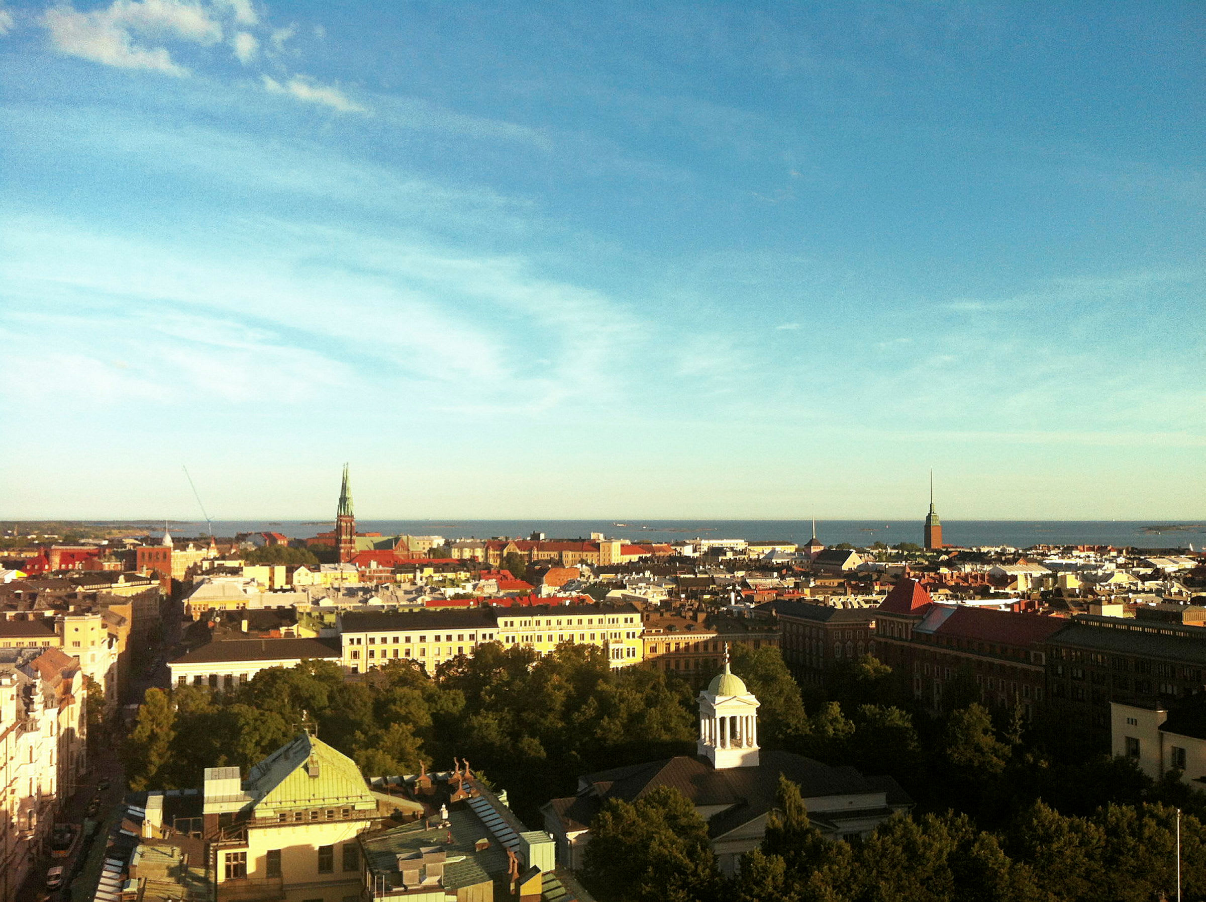 Utsikt över en stad med kyrktorn, byggnader och hav i bakgrunden. (AI-genererad text)