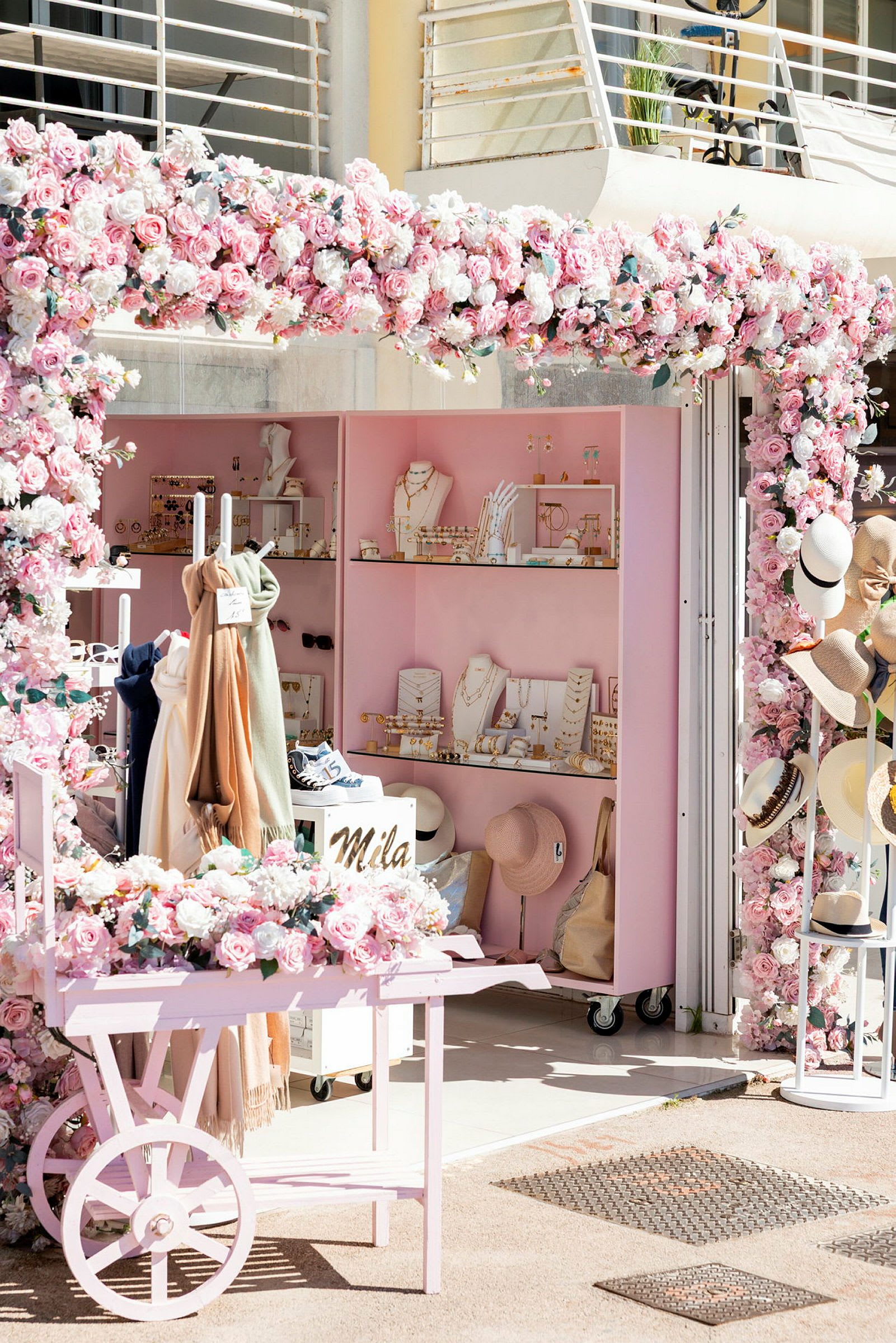 En butik med rosa dekorationer och blommor, smycken och accessoarer visas. (AI-genererad text)