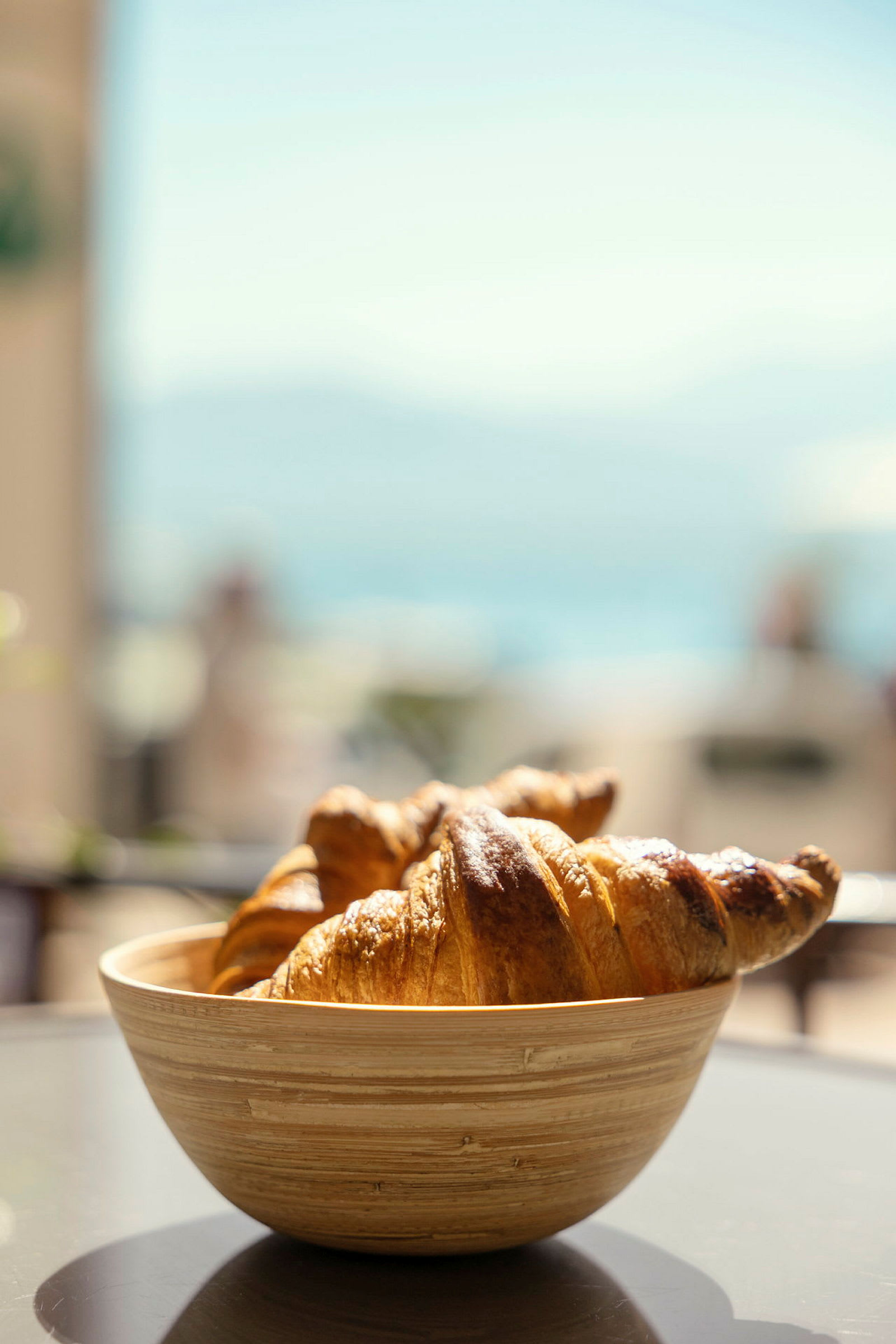 En skål med croissanter står på ett bord med suddig bakgrund. (AI-genererad text)