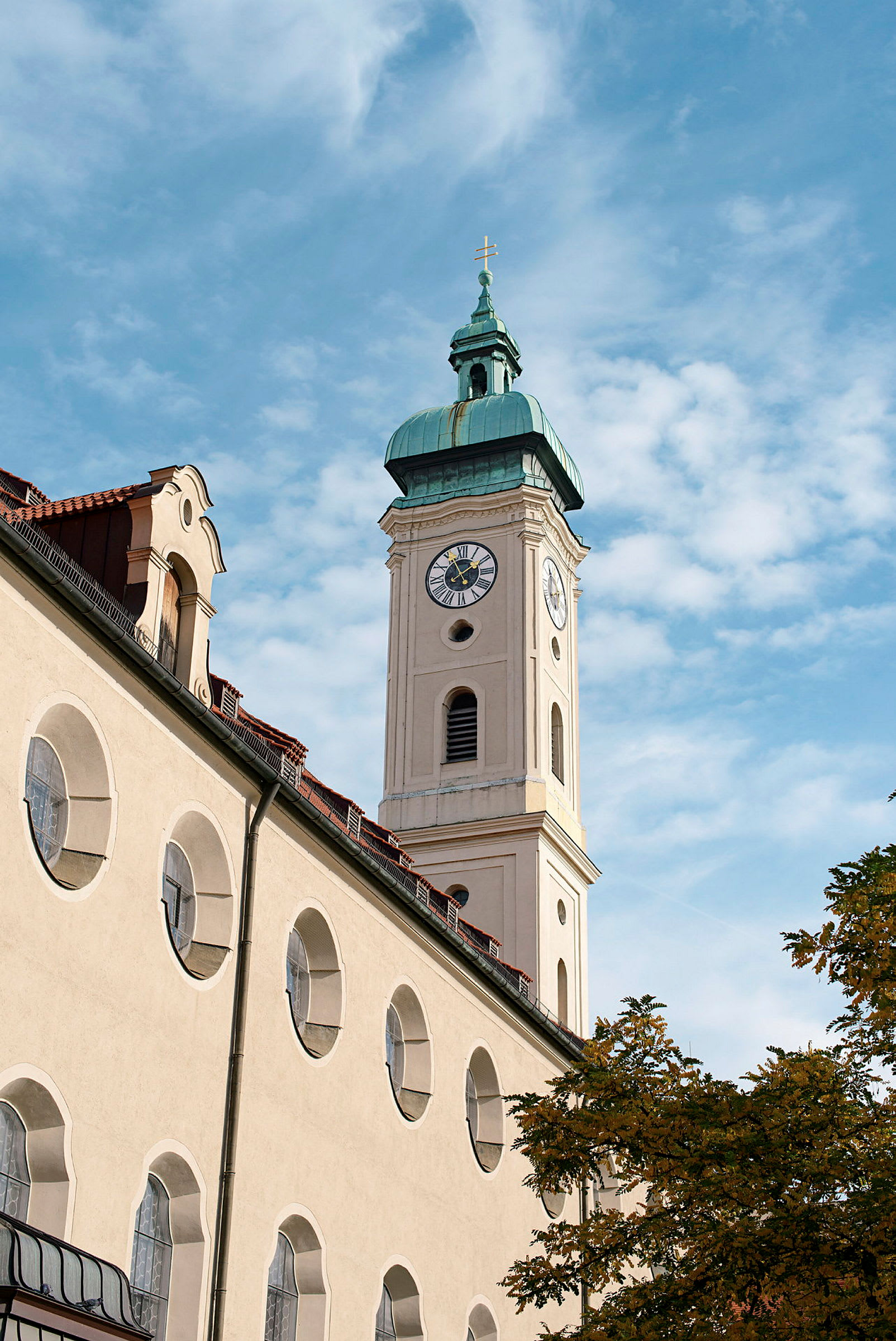 En kyrka med en klockstapel och en spir med ett kors på toppen, mot en blå himmel. (AI-genererad text)