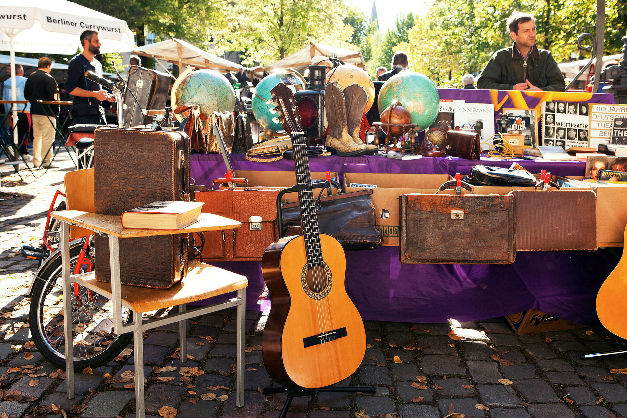 En marknadsstånd med vintageobjekt, inklusive resväskor, jordglober och en gitarr. (AI-genererad text)