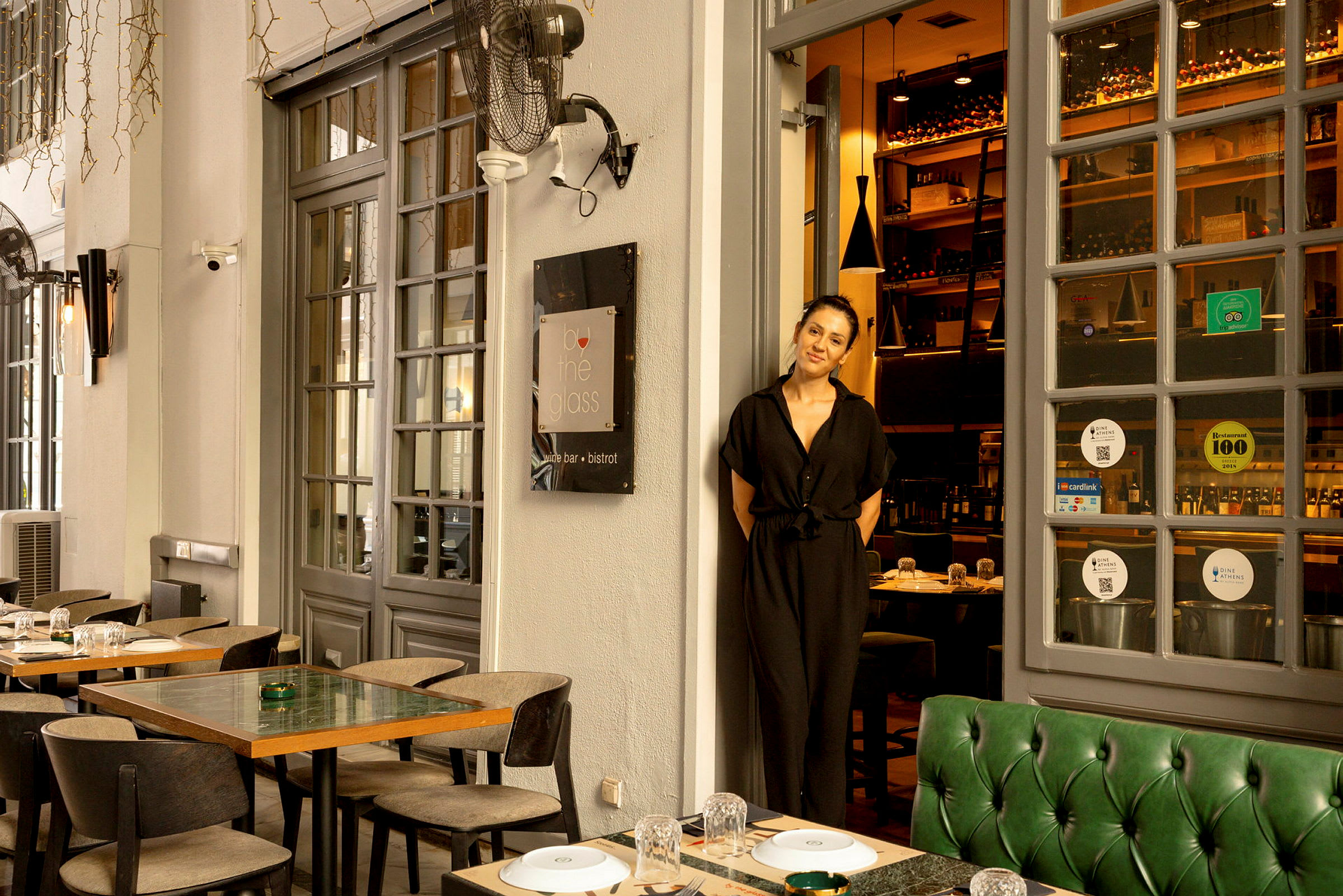 En restaurang med utomhusbord och glasdörrar som leder in till en vinbar. (AI-genererad text)