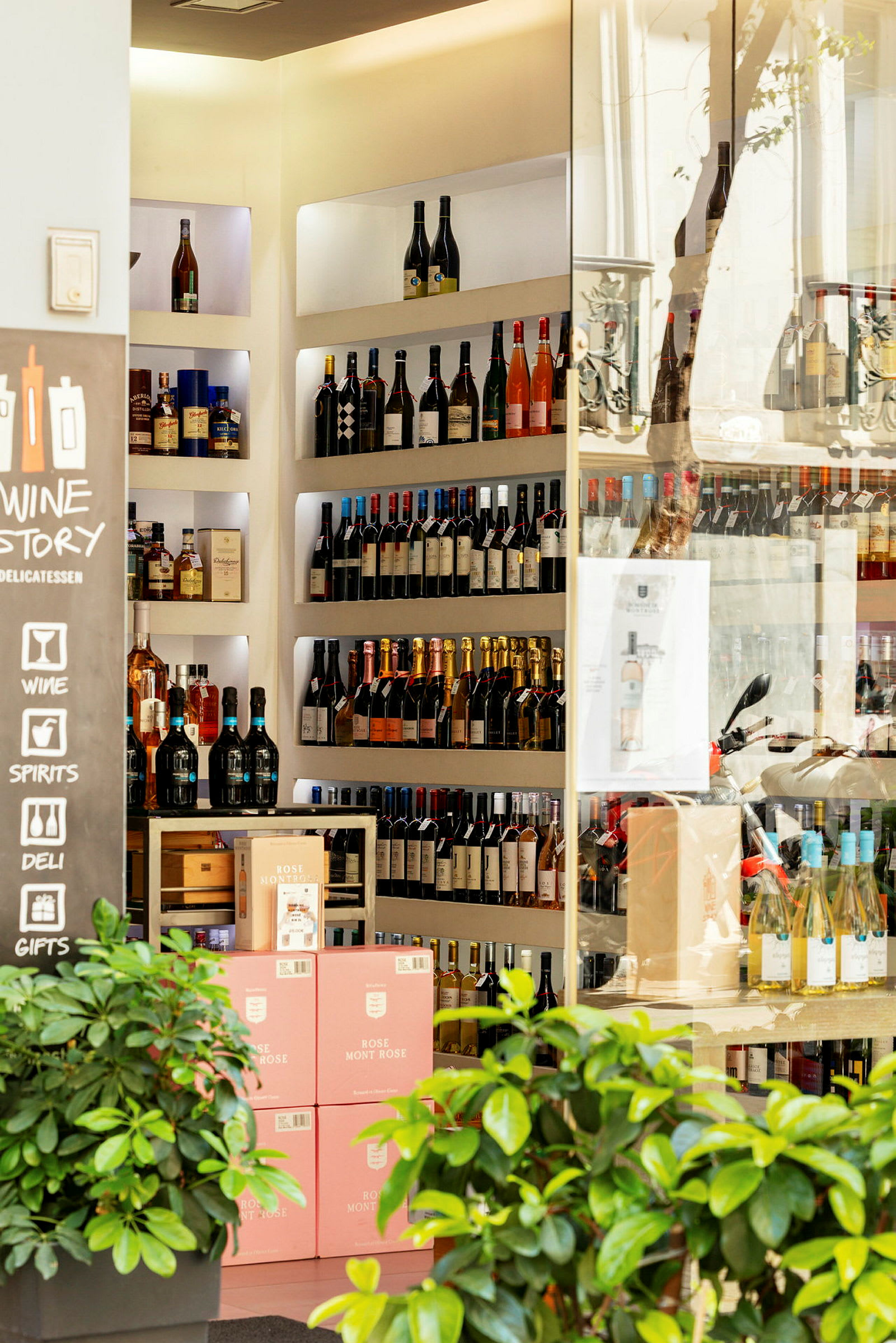 Ett vin- och spritbutik med hyllor fyllda med flaskor samt kartonger med rosa etiketter. (AI-genererad text)
