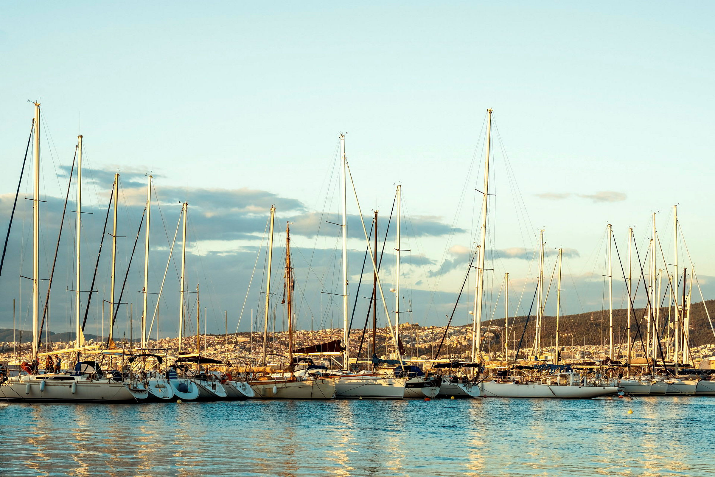 Segelbåtar förtöjda i en hamn med stad i bakgrunden. (AI-genererad text)