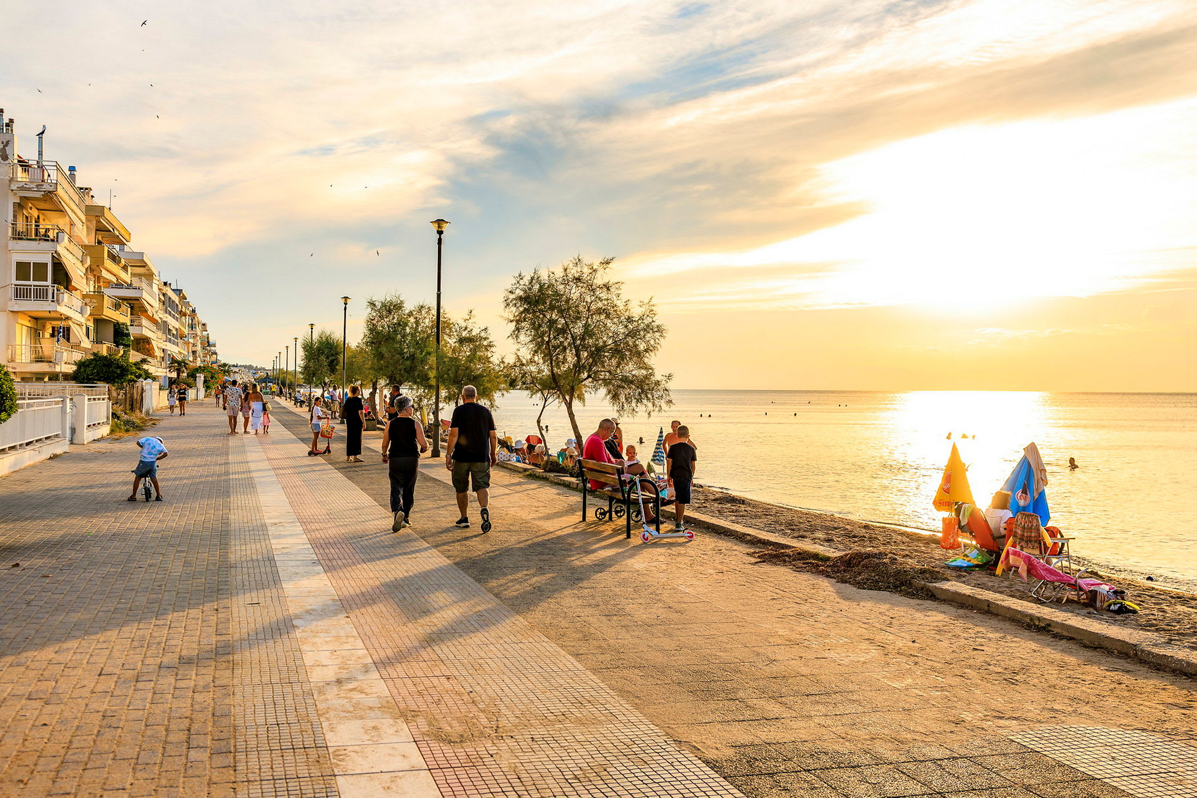 Promenadstråk vid havet med människor som går och sitter på bänkar. (AI-genererad text)