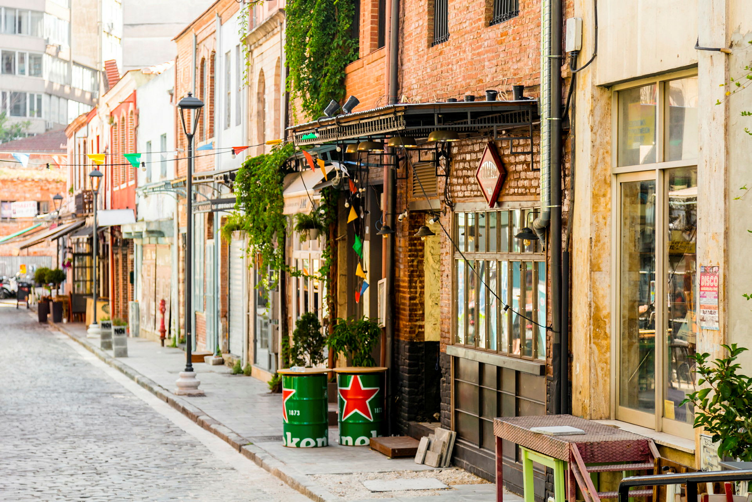 En gata med byggnader dekorerade av färgglada flaggor och tunnor med Heineken-logotypen. (AI-genererad text)