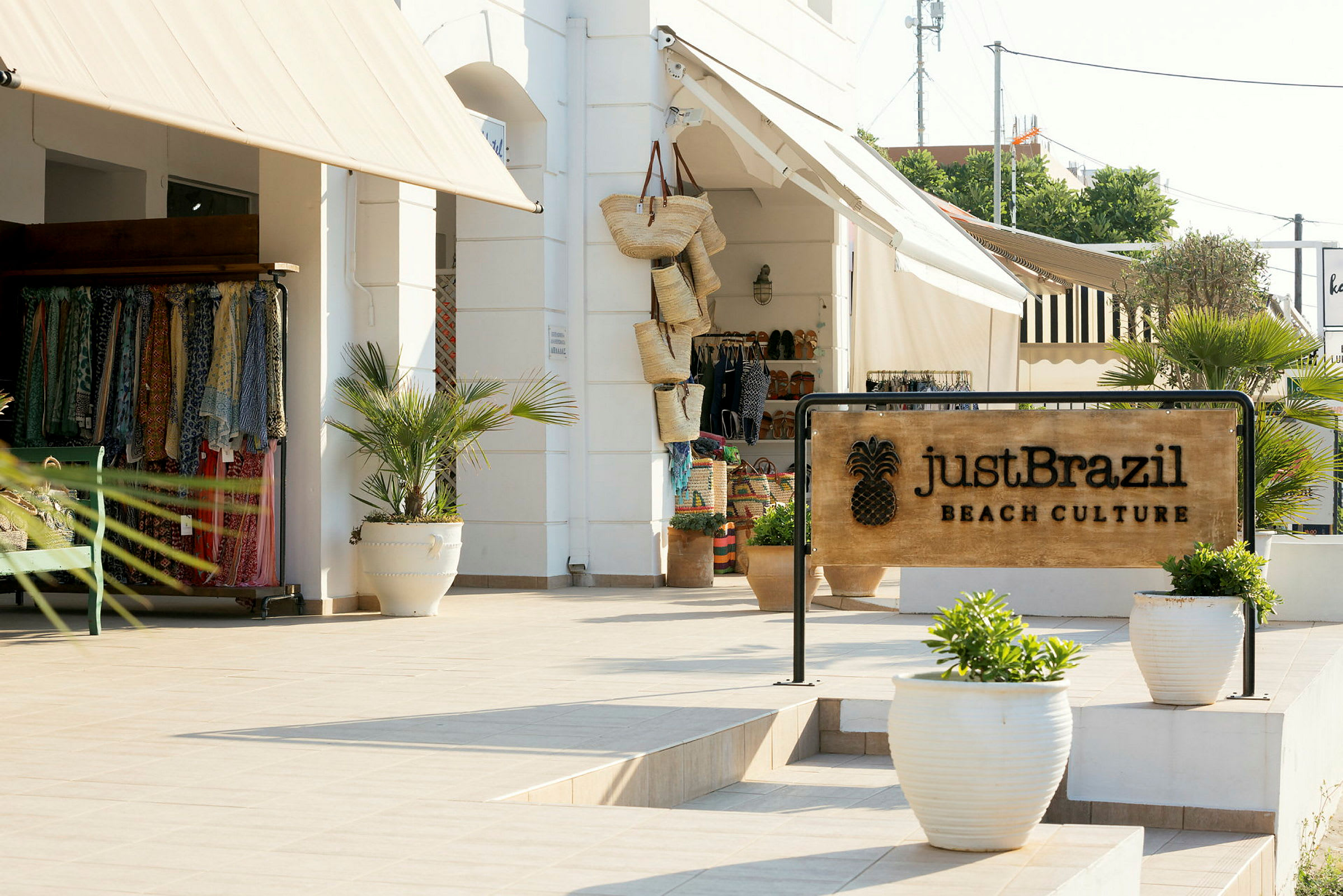 Skylt med texten 'Just Brazil Beach Culture' framför en butik med bomullskläder och korgar. (AI-genererad text)