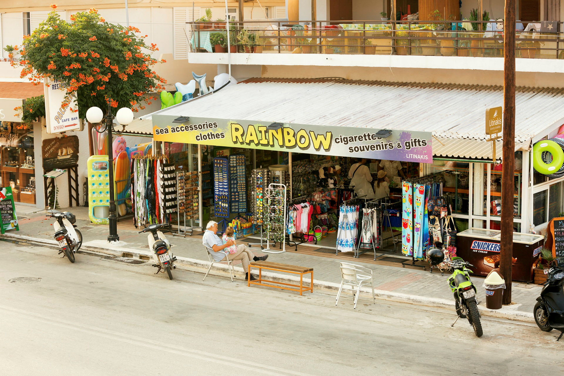 En butik med texten 'Rainbow' på markisen säljer souvenirer och strandtillbehör. (AI-genererad text)