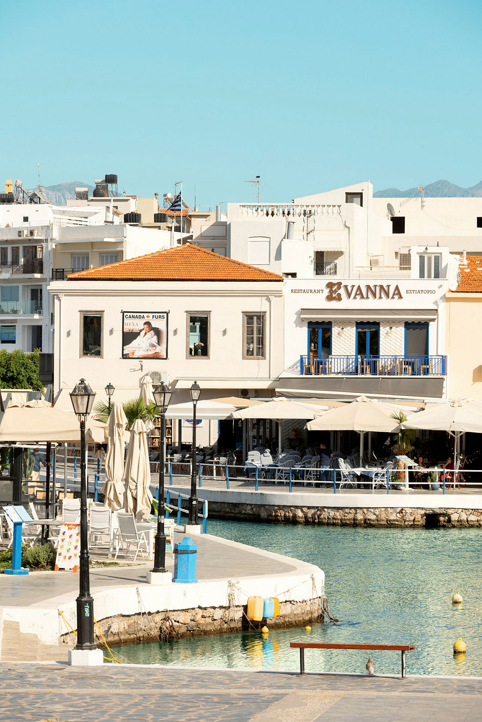 Vy över en liten hamn med sittplatser och restaurang Vanna. (AI-genererad text)