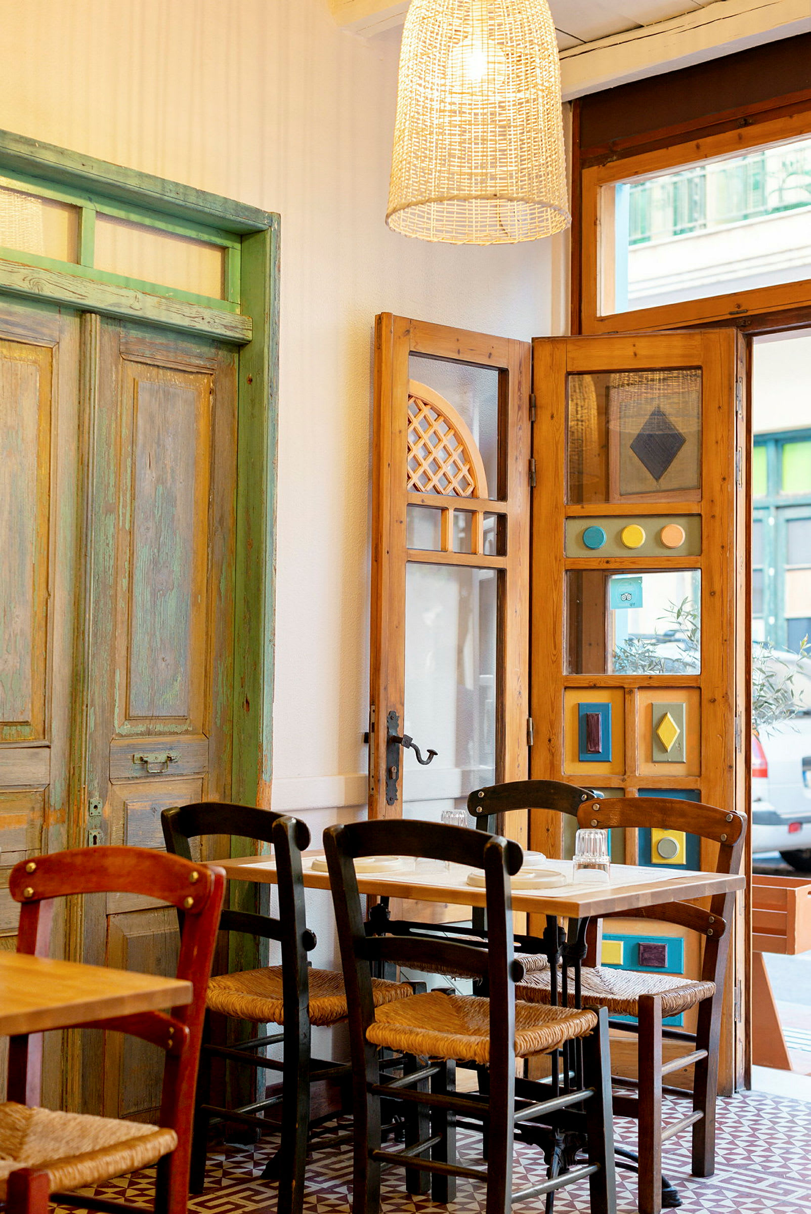 Interiör av en restaurang med trästolar och ett bord framför dekorativa dörrar och fönster. (AI-genererad text)