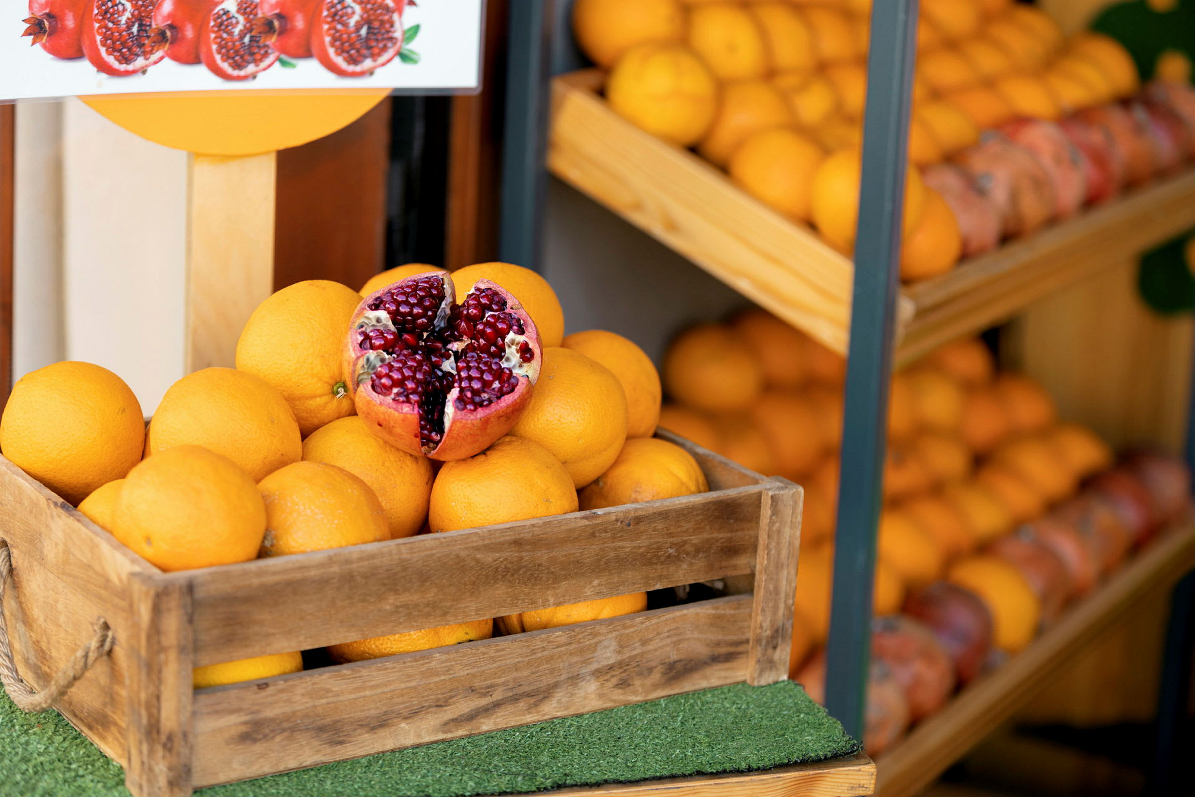 En trälåda fylld med apelsiner, en öppnad granatäpple placerad ovanpå. (AI-genererad text)