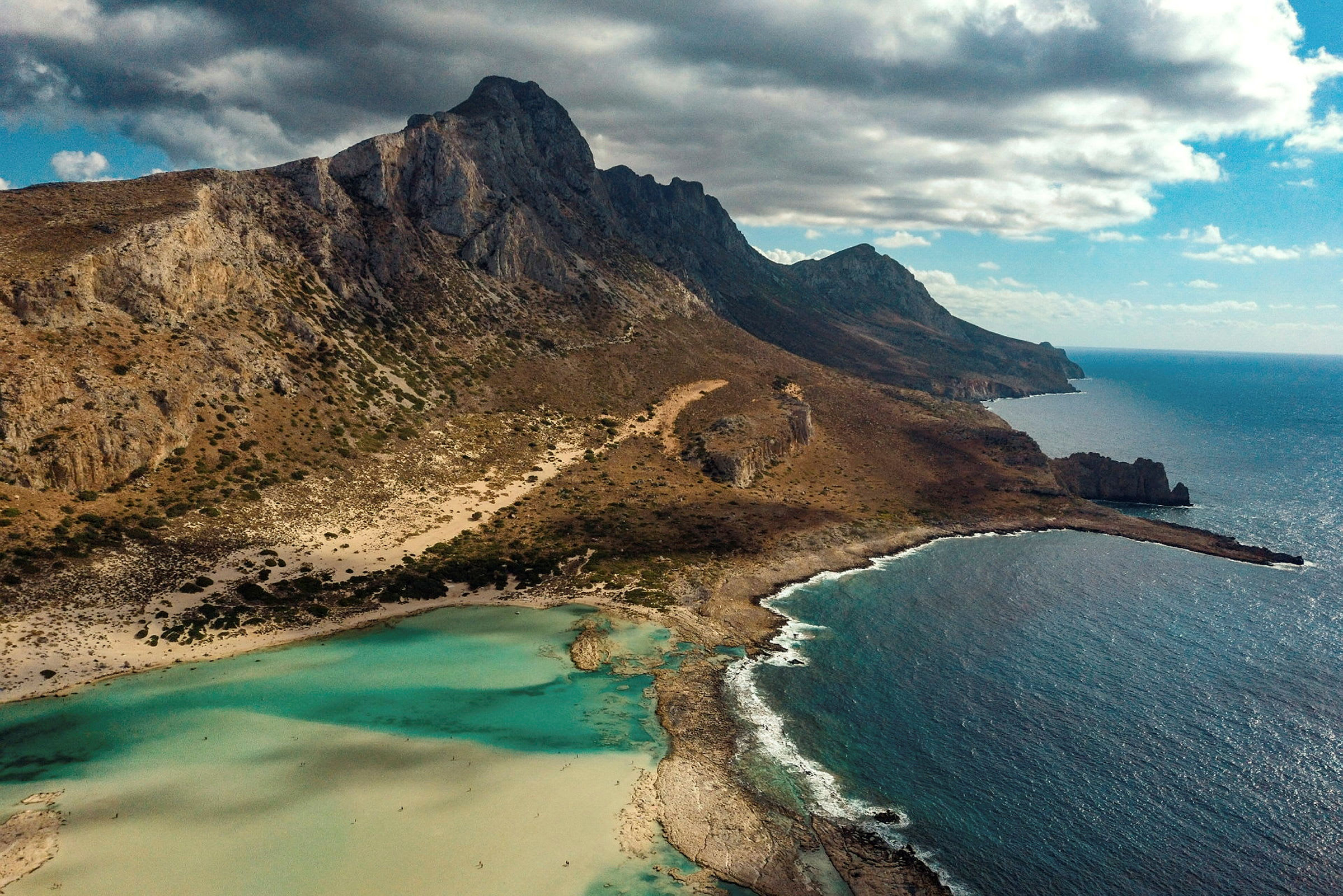 Bilden visar en kustlandskap med klippor, en strand och turkosvatten. (AI-genererad text)