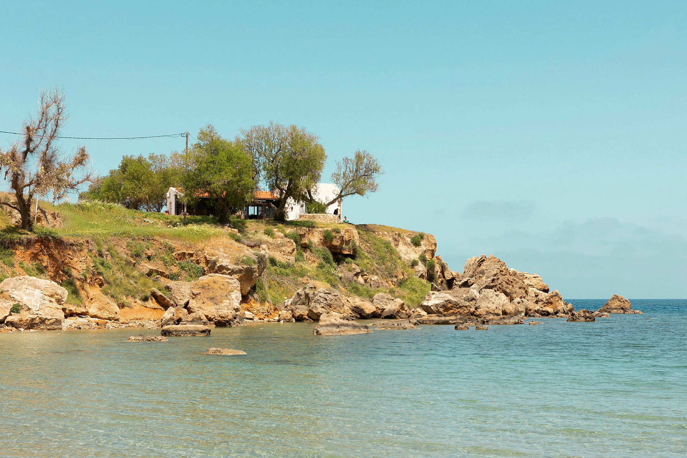 Ett hus på en klippa vid havet med klart blått vatten. (AI-genererad text)