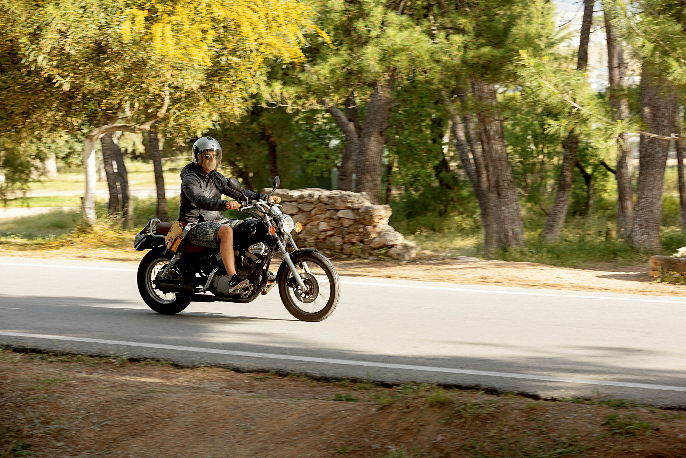 En person kör en motorcykel på en väg omgiven av grönska. (AI-genererad text)
