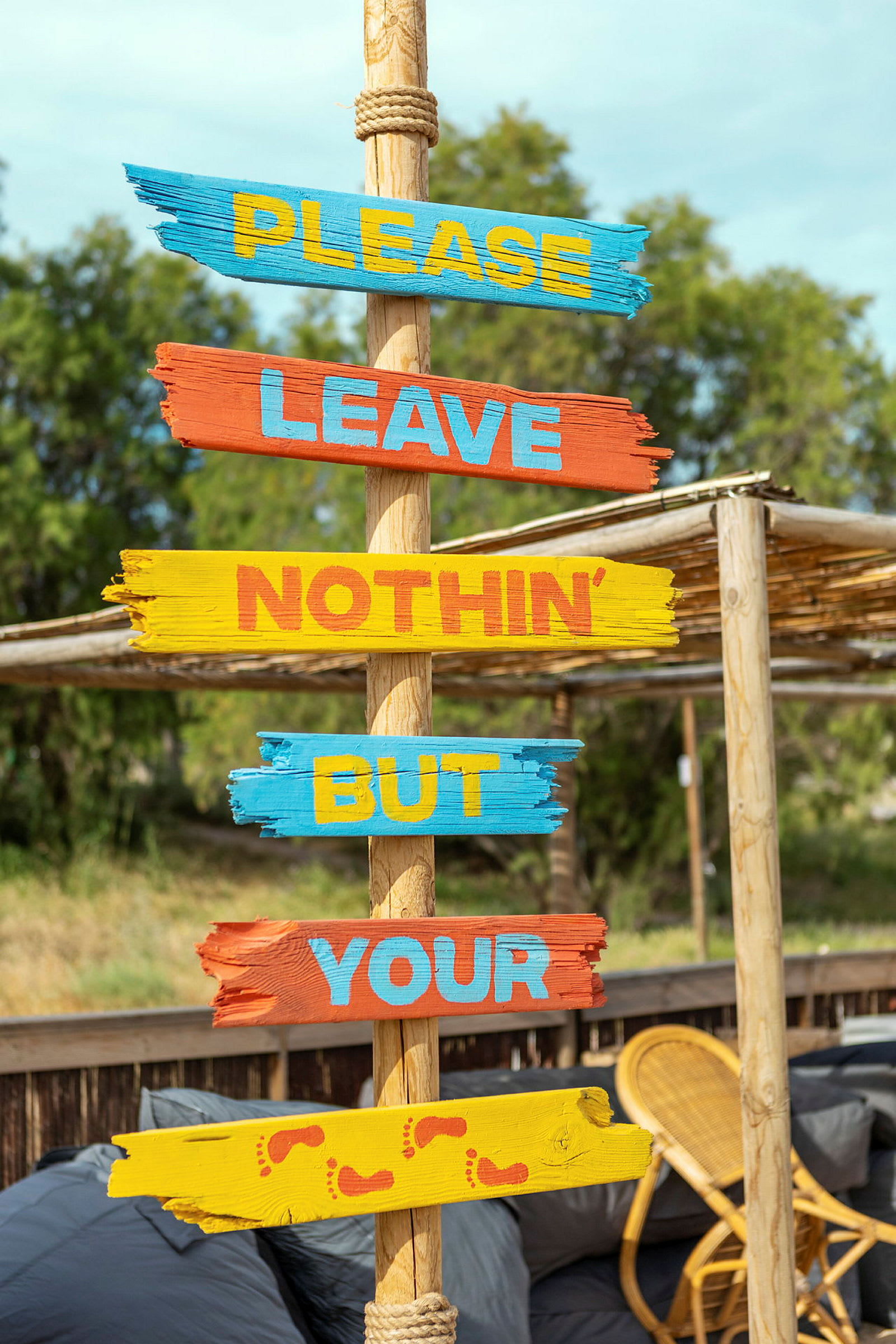 Skylt med texten 'Please leave nothin’ but your', målade på färgglada träplankor. (AI-genererad text)