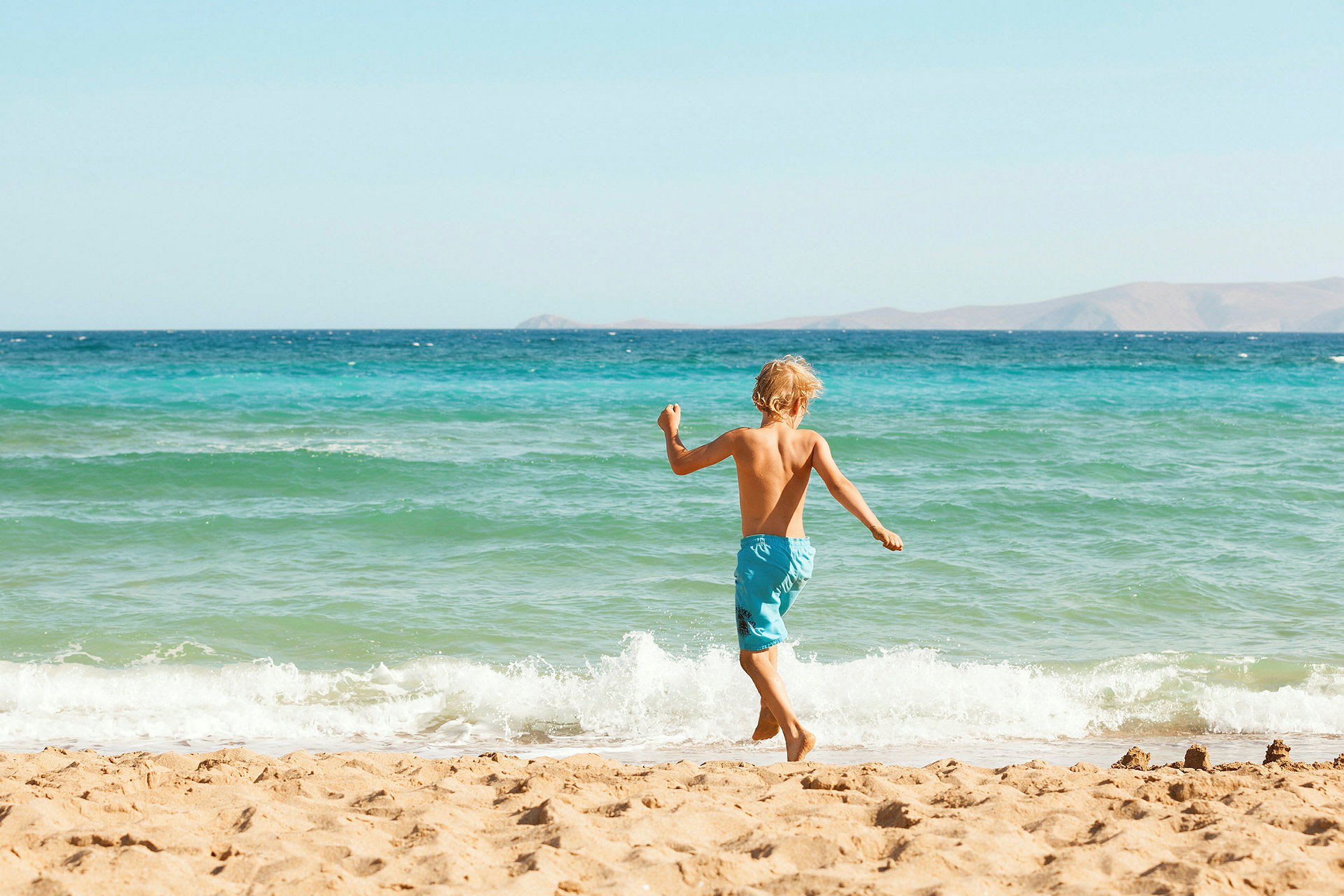 En pojke springer på stranden nära havet. (AI-genererad text)