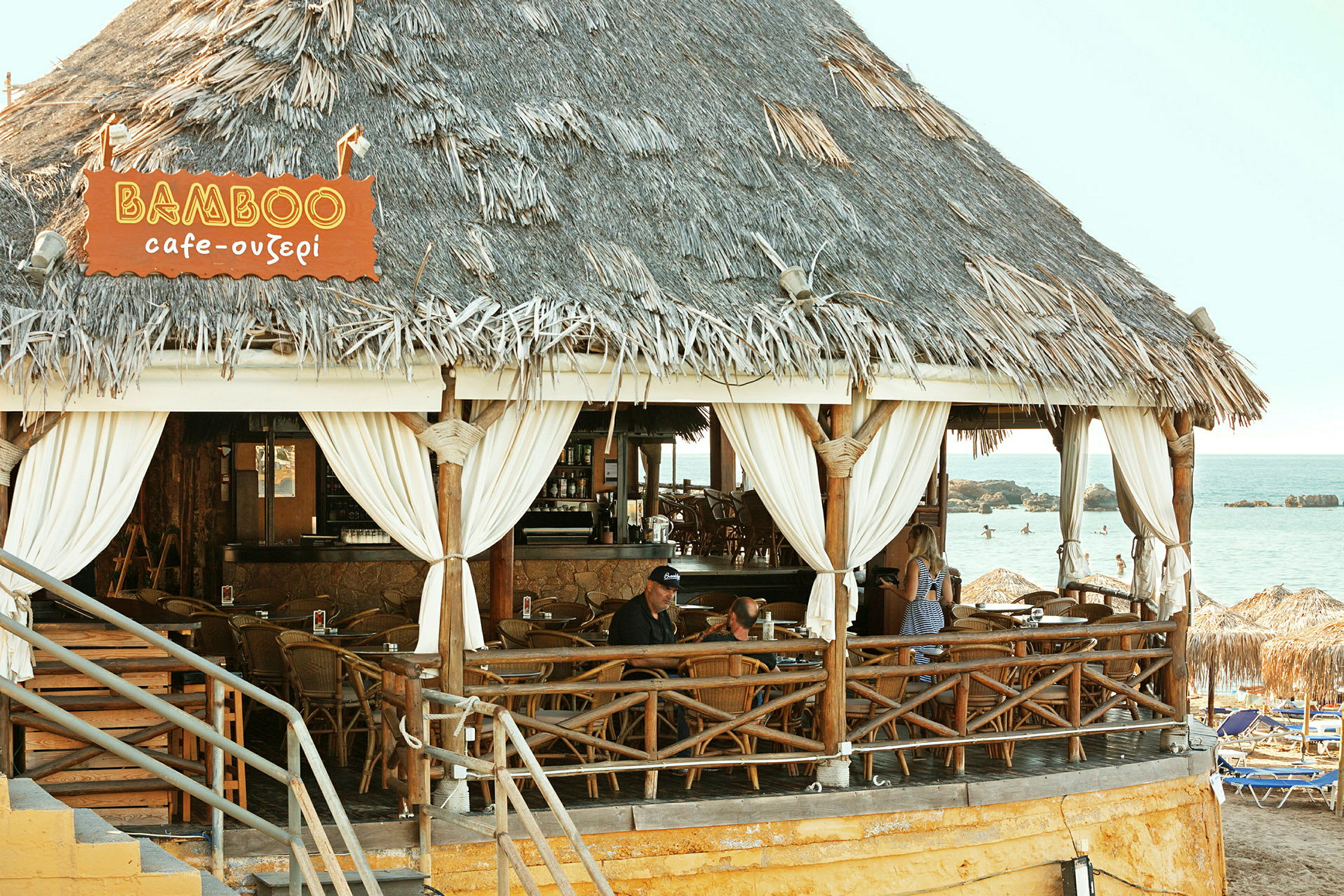 En strandbar med halmtak och träinredning vid havet. (AI-genererad text)