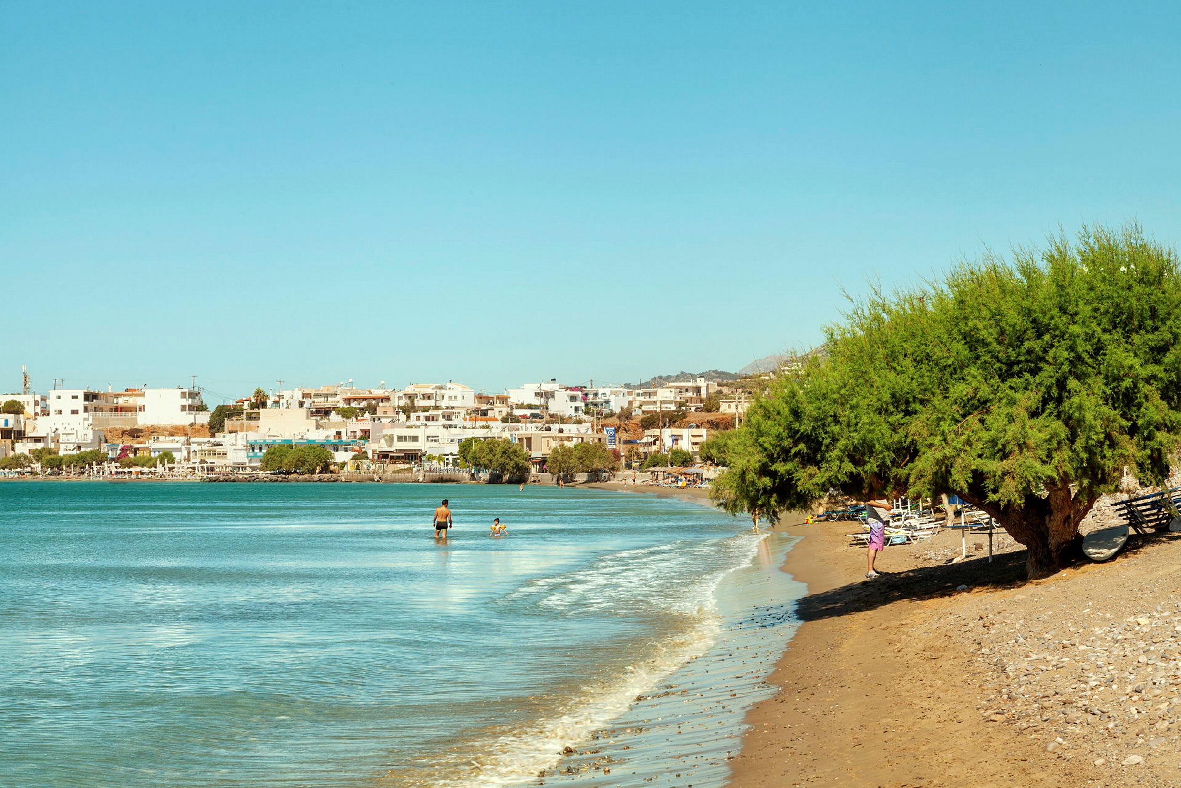 En kuststräcka med strand, hav och byggnader i bakgrunden. (AI-genererad text)