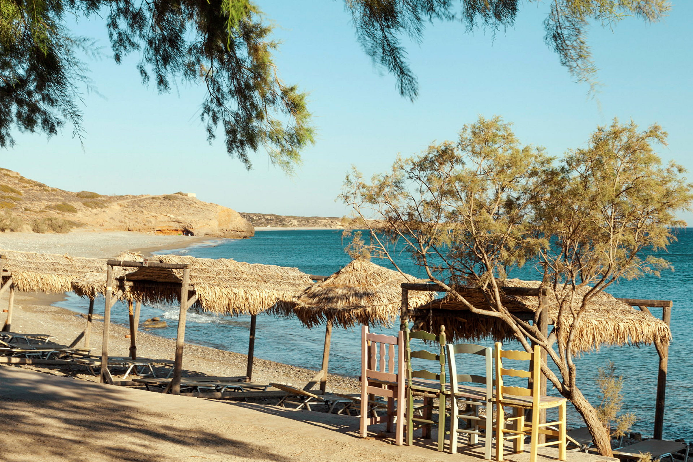 En strand med parasoller av halm nära klart blått vatten. (AI-genererad text)