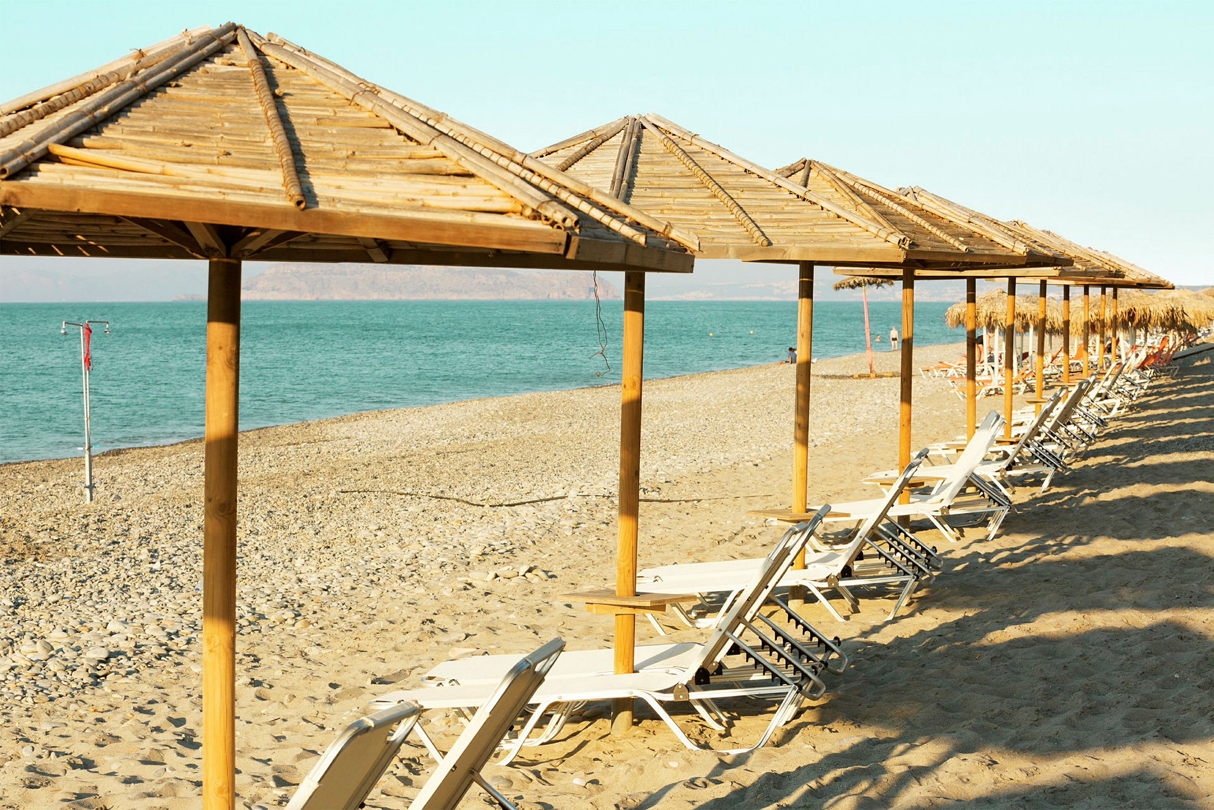 Strand med parasoller och solstolar vid havet. (AI-genererad text)