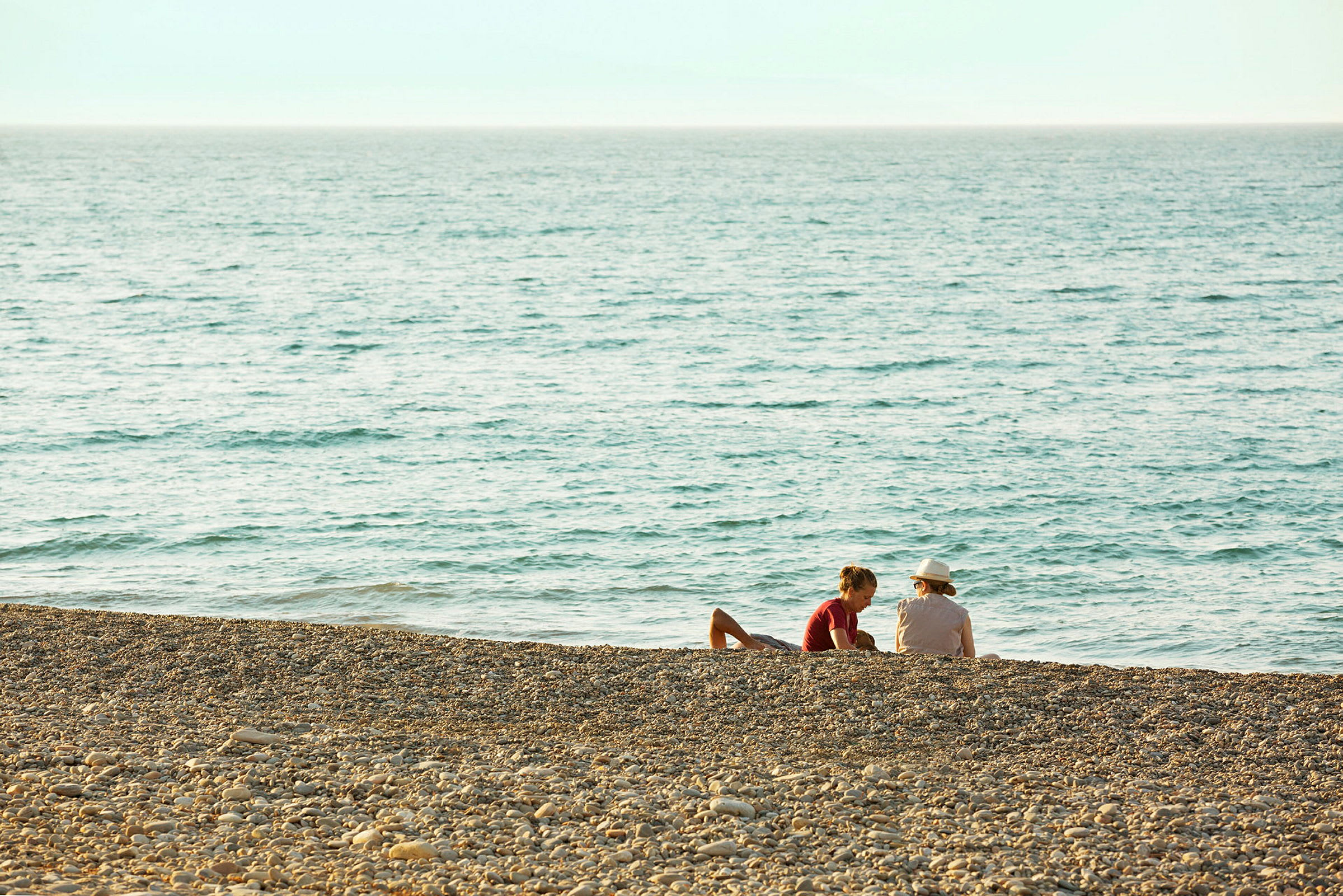 Två personer sitter på en stenstrand vid havet. (AI-genererad text)