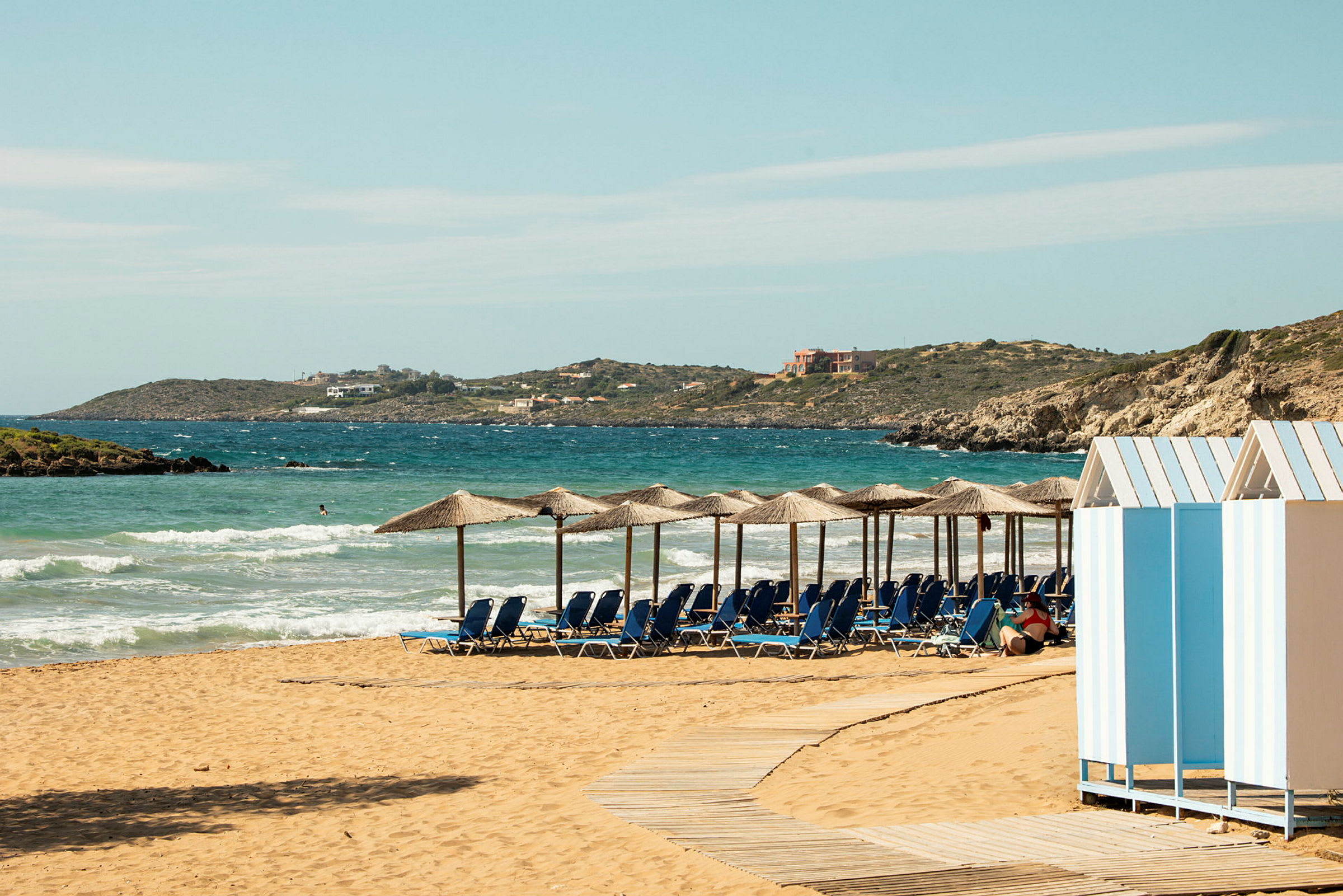 En strand med solstolar och parasoll framför en blå ocean. (AI-genererad text)