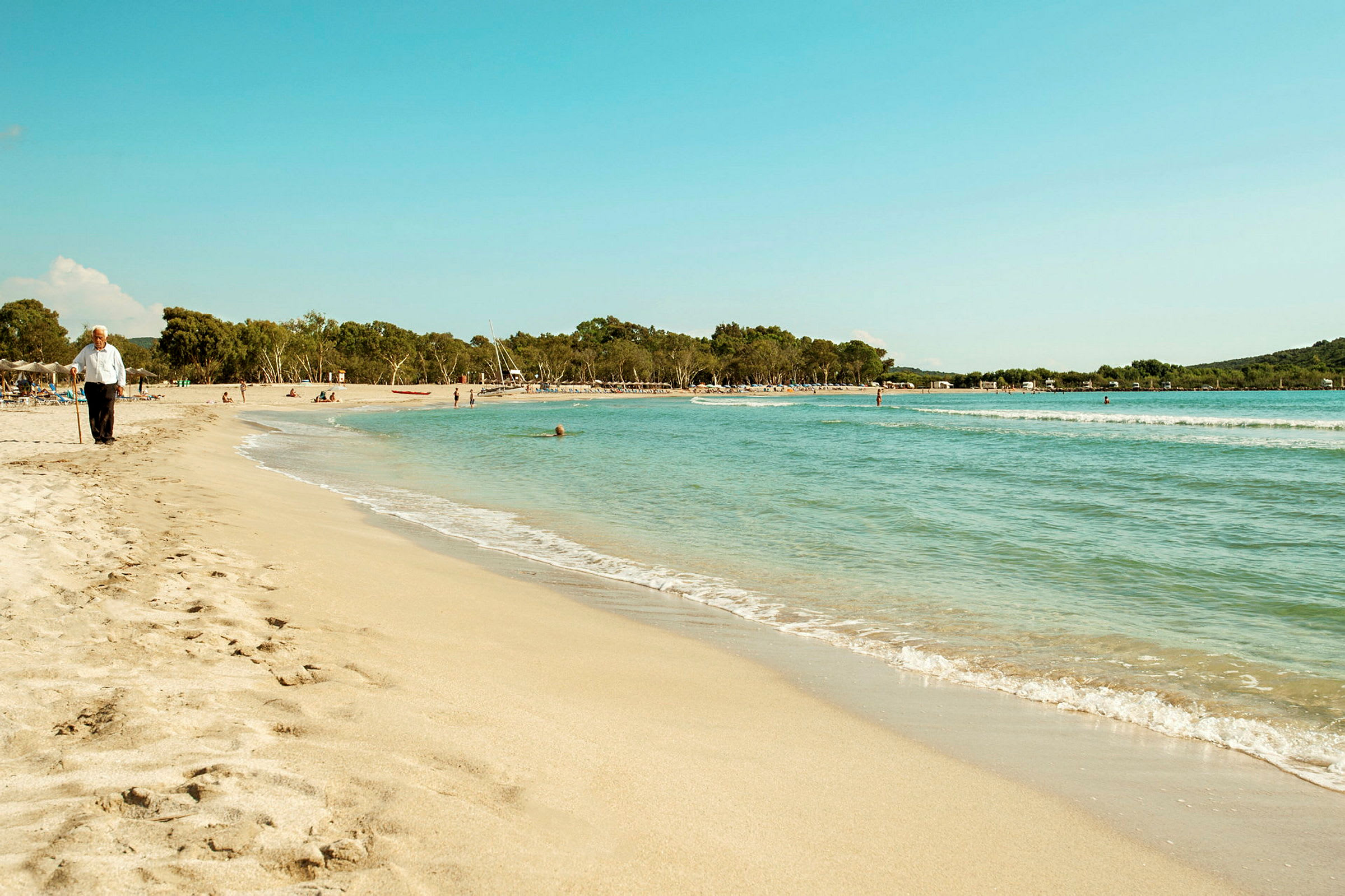 En sandstrand med en gammal man som går nära vattenbrynet. (AI-genererad text)