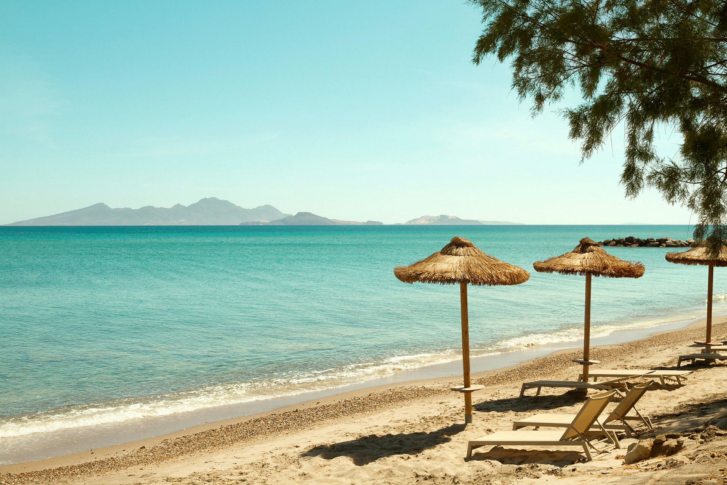 Strand med parasoller och solsängar vid havet. (AI-genererad text)