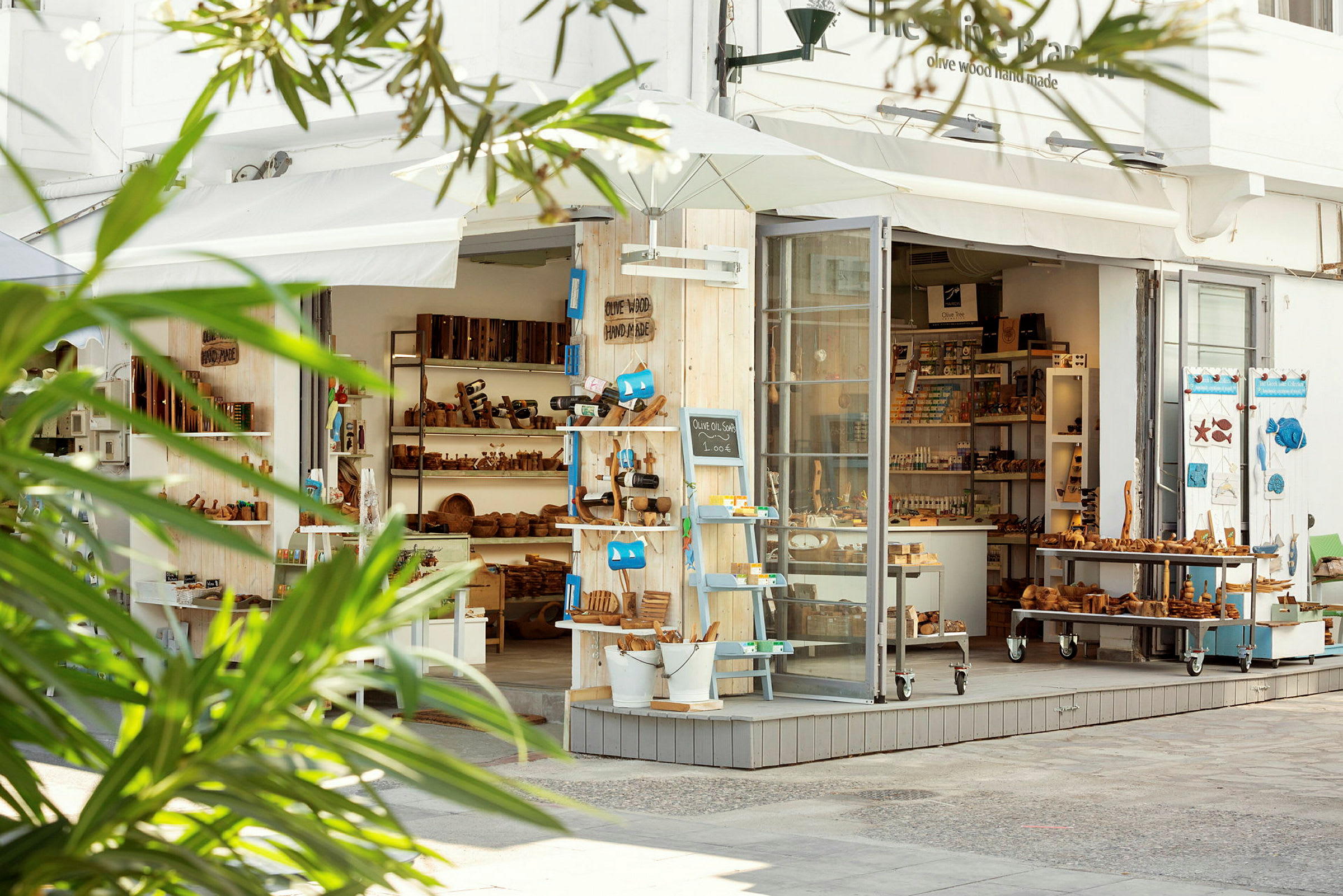 En butik med träprodukter och souvenirer, med ett öppet glasparti och grönska i förgrunden. (AI-genererad text)