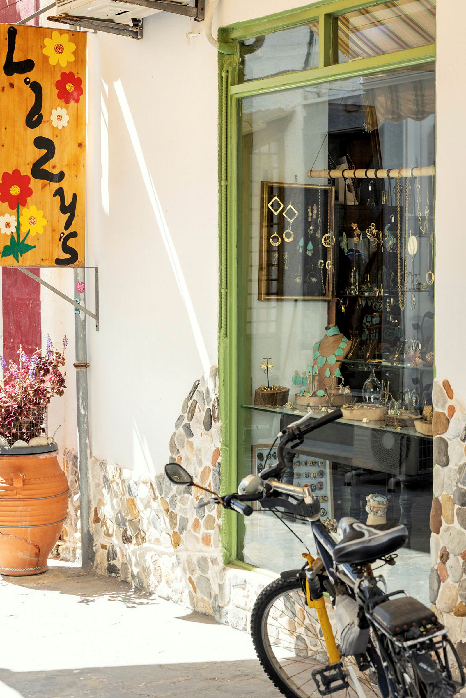 Bilden visar en cykel parkerad framför en butik med ett grönt skyltfönster och dekorativa föremål. (AI-genererad text)