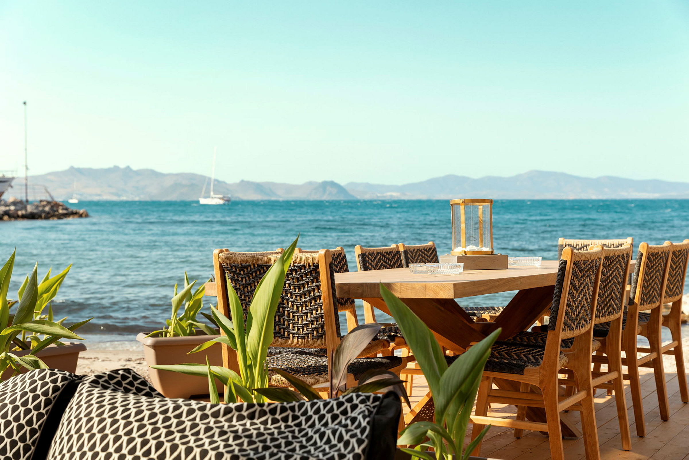 Träbord med stolar på en terrass nära havet. (AI-genererad text)