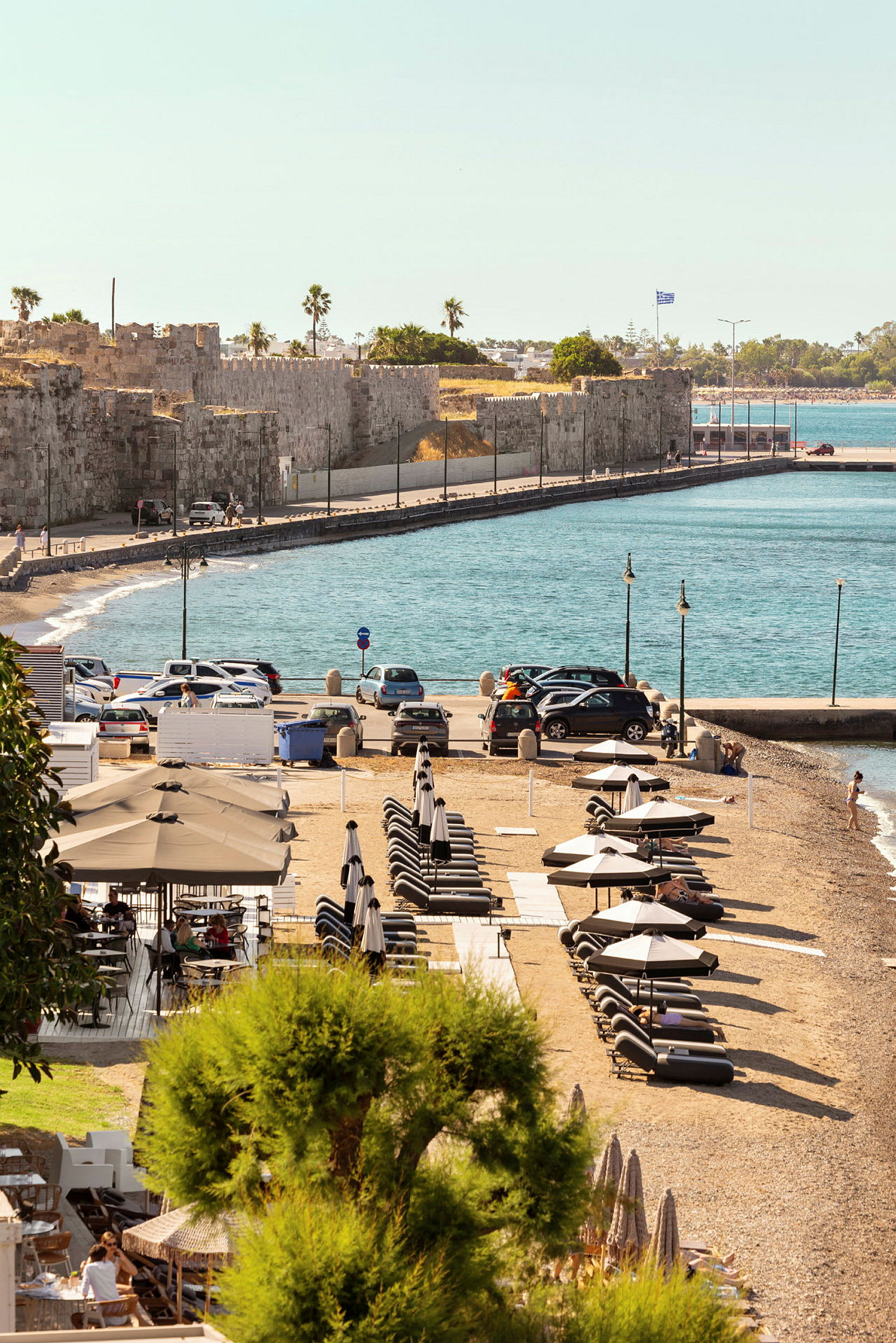 Strand med solstolar och parasoller nära klippväggar och blått hav. (AI-genererad text)