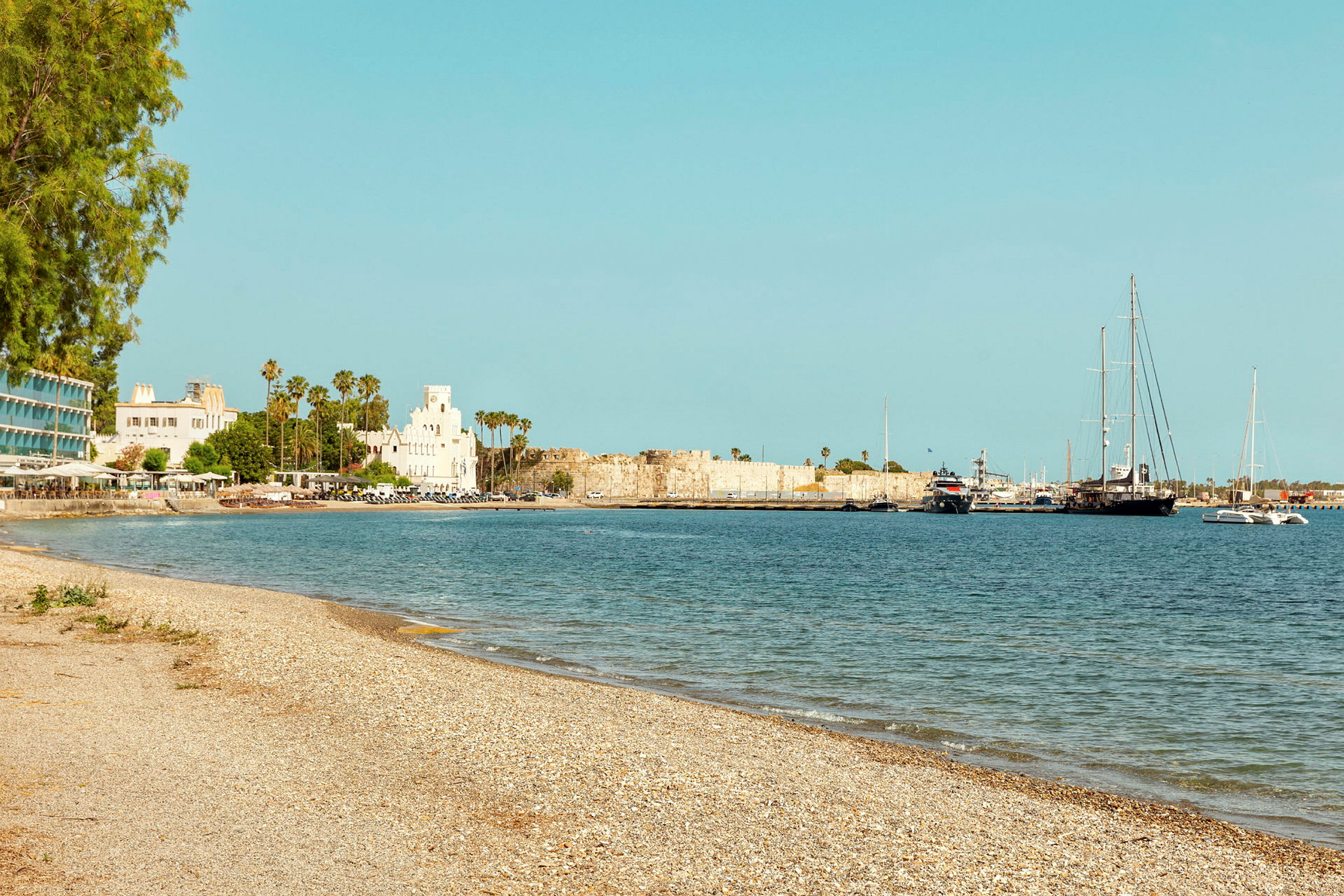 Strand med utsikt över vatten, båtar och byggnader. (AI-genererad text)