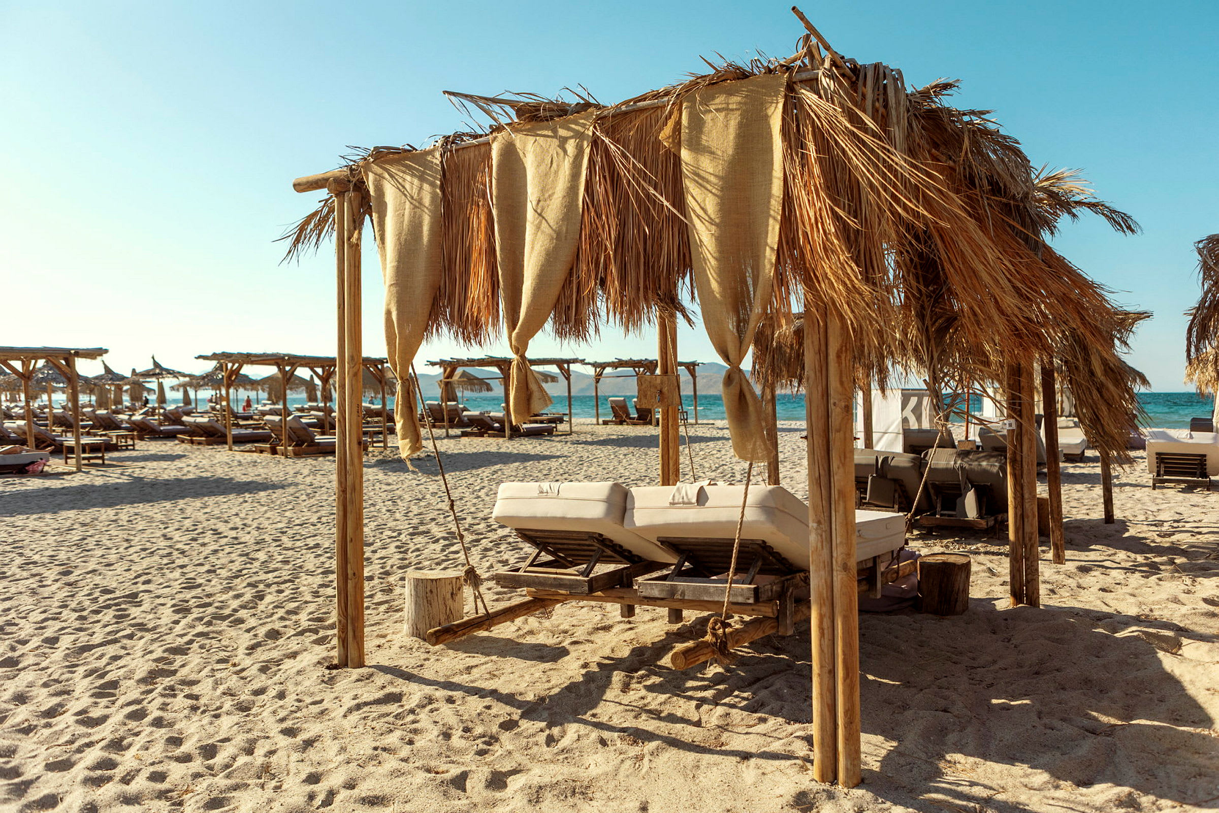 Strand med jutevävsparasoller och solsängar. (AI-genererad text)