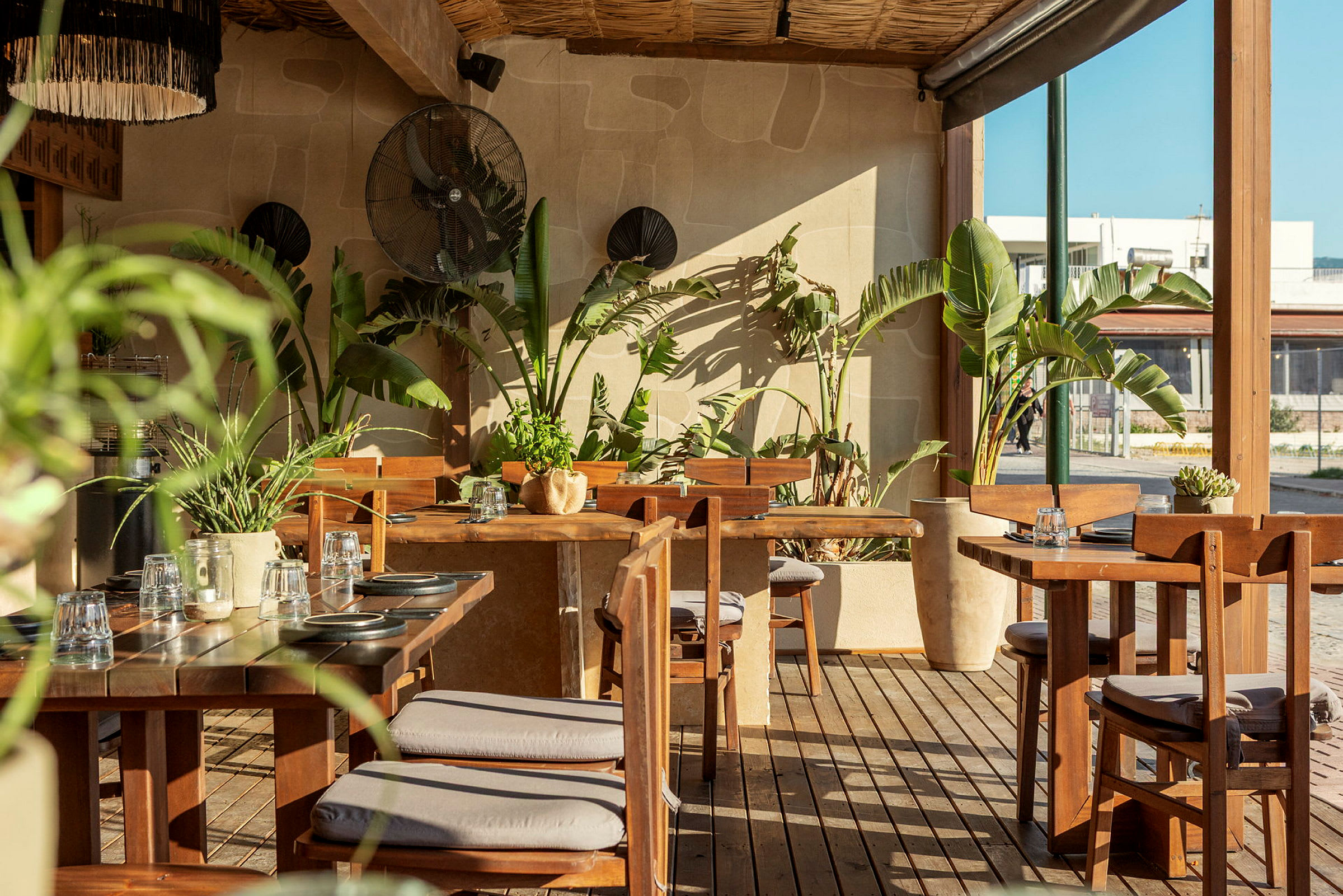 En utomhusrestaurang med trämöbler och gröna växter. (AI-genererad text)