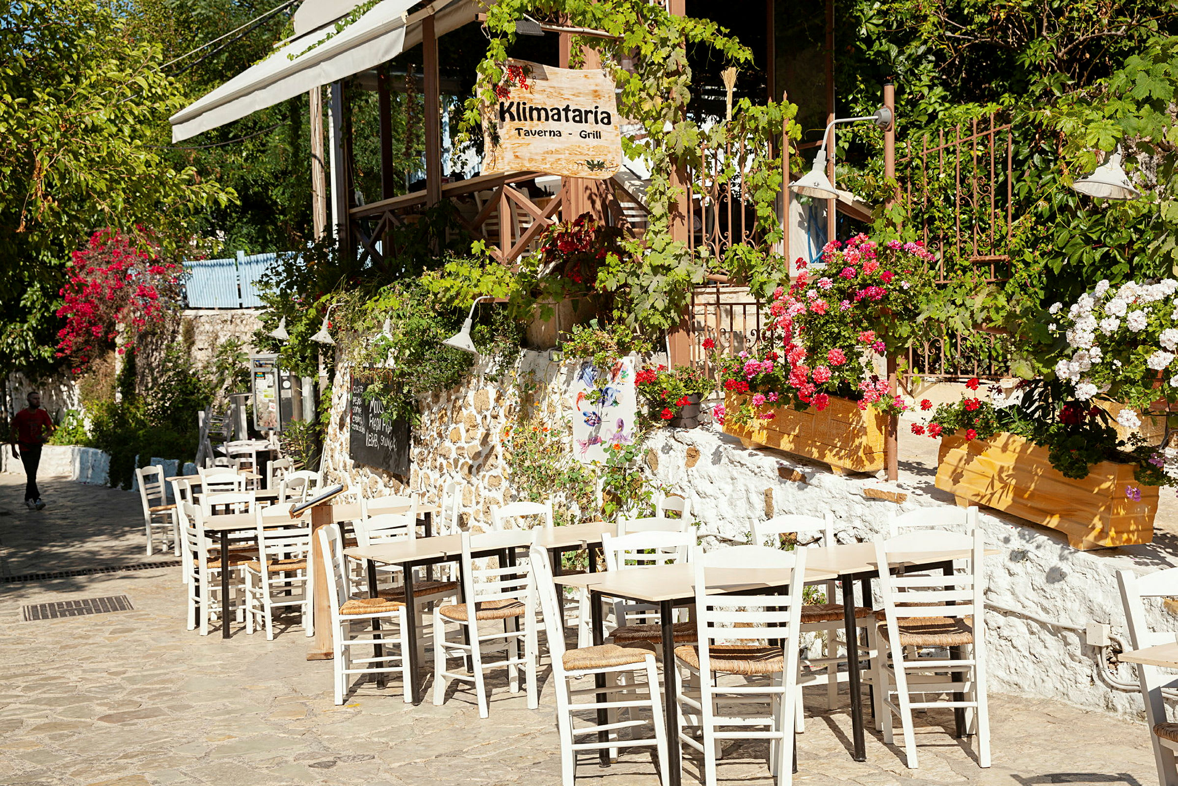 Uteservering vid en taverna, omgiven av blommande växter. (AI-genererad text)