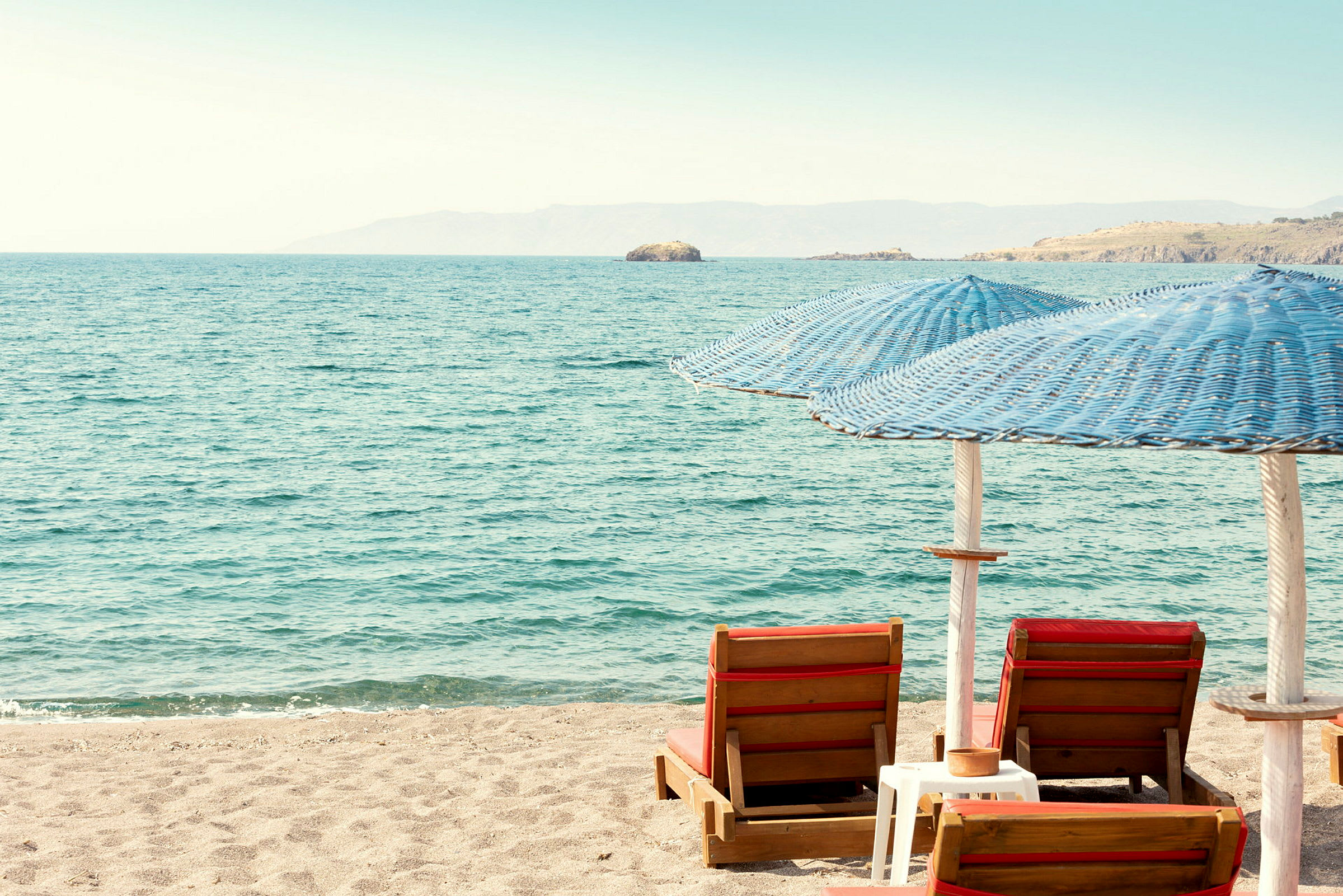 Strand med två solstolar och parasoller vid havet. (AI-genererad text)