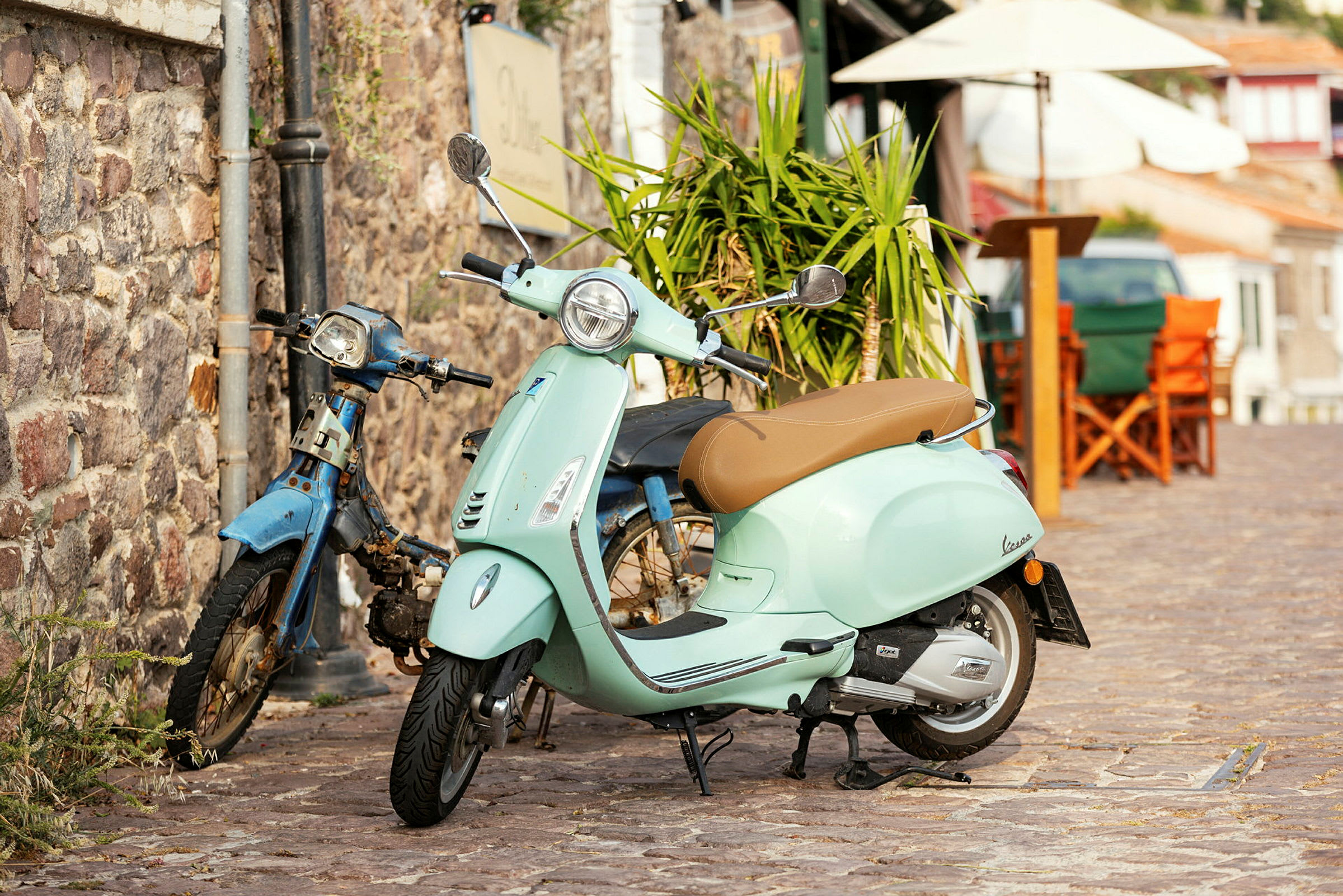 En ljusgrön scooter står parkerad bredvid en gammal blå moped. (AI-genererad text)