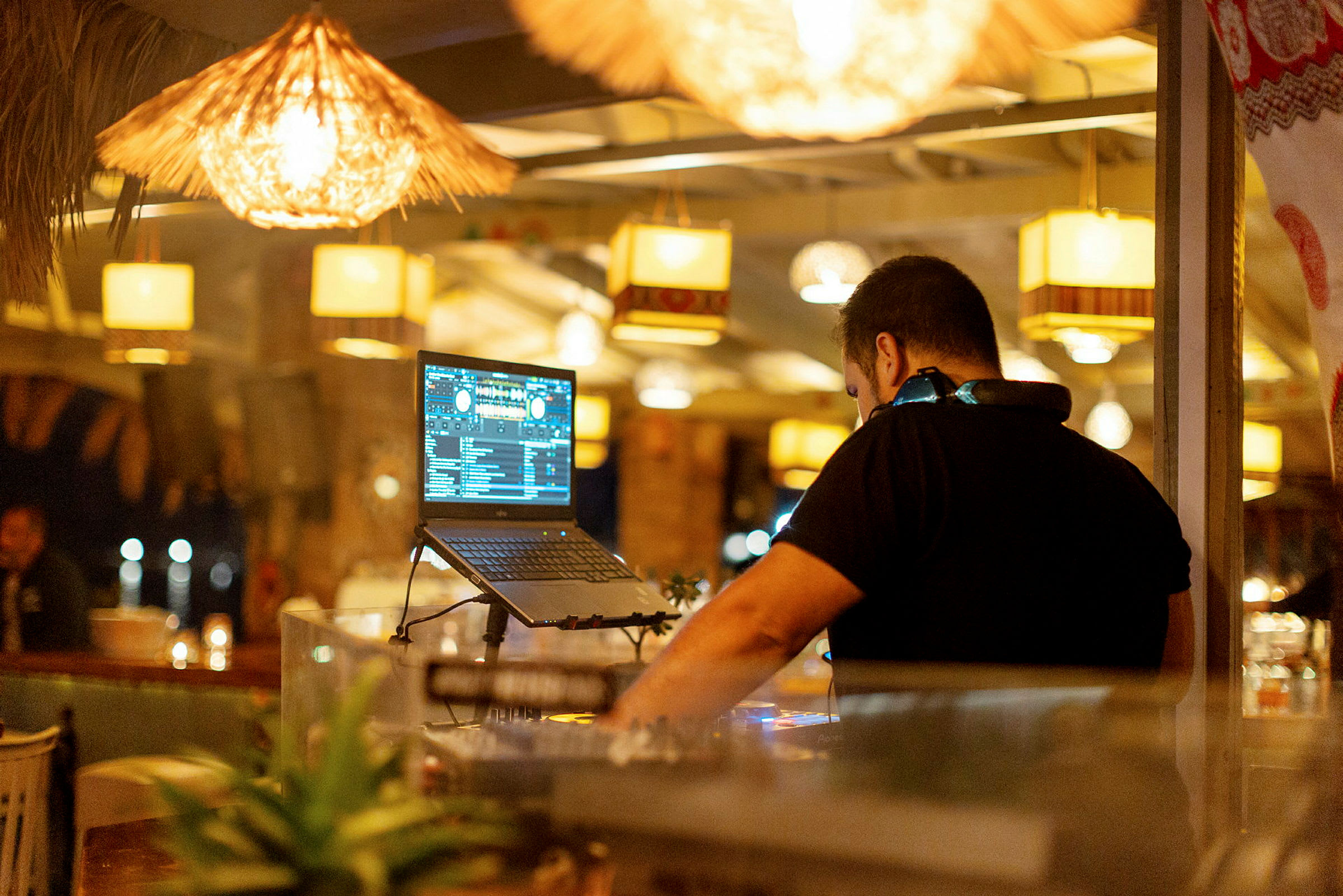 Person vid ett DJ-bord med upplyst laptop. (AI-genererad text)