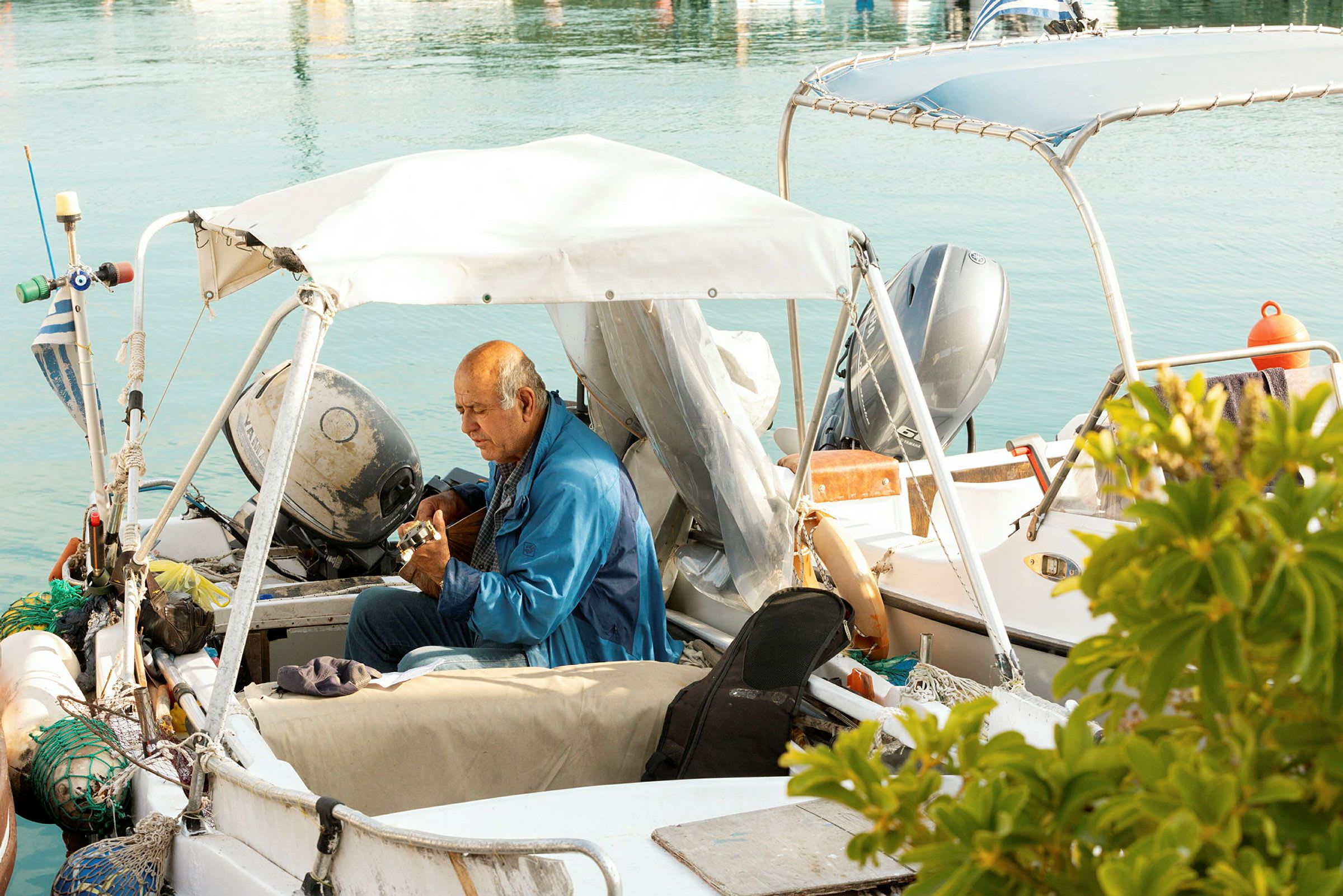 En person sitter i en båt med fiskeredskap och motor. (AI-genererad text)