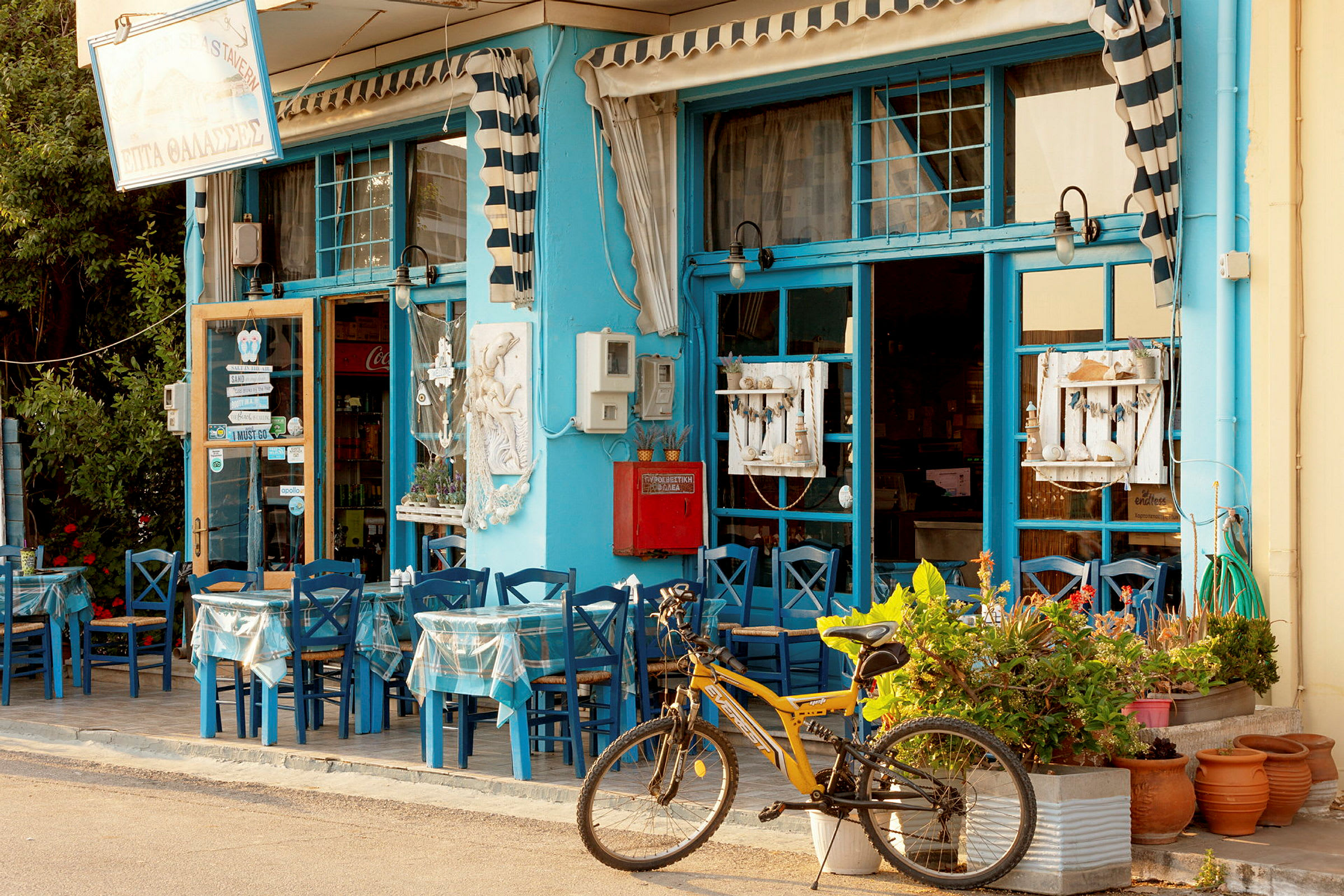 En gul cykel står framför en restaurang med blå möbler och dekorationer. (AI-genererad text)