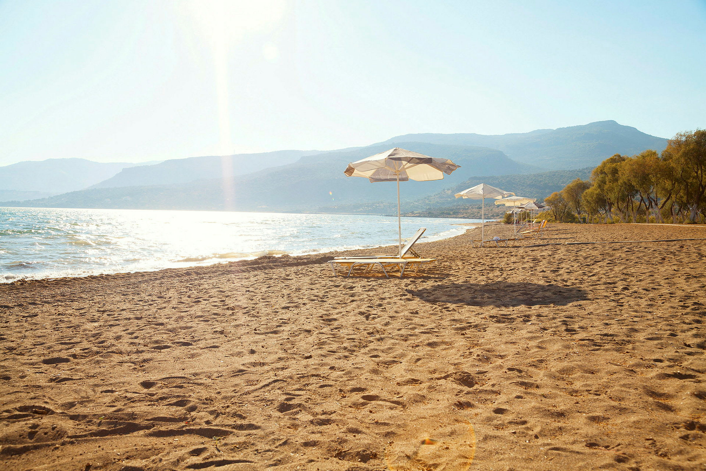 En sandstrand med solstolar och parasoller nära havet. (AI-genererad text)
