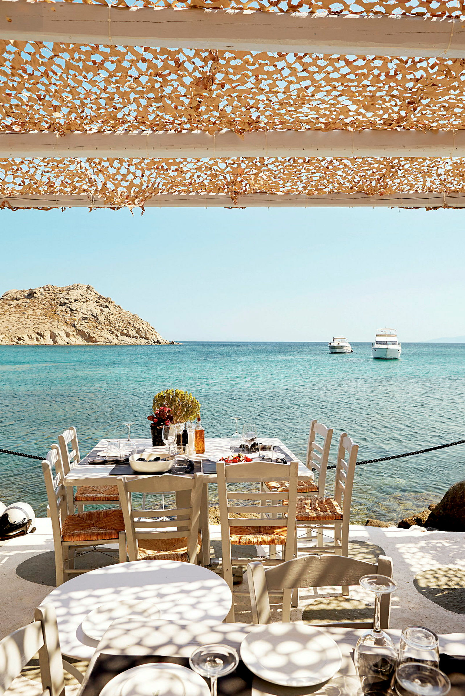 Ett dukat bord vid havet med öar i bakgrunden. (AI-genererad text)