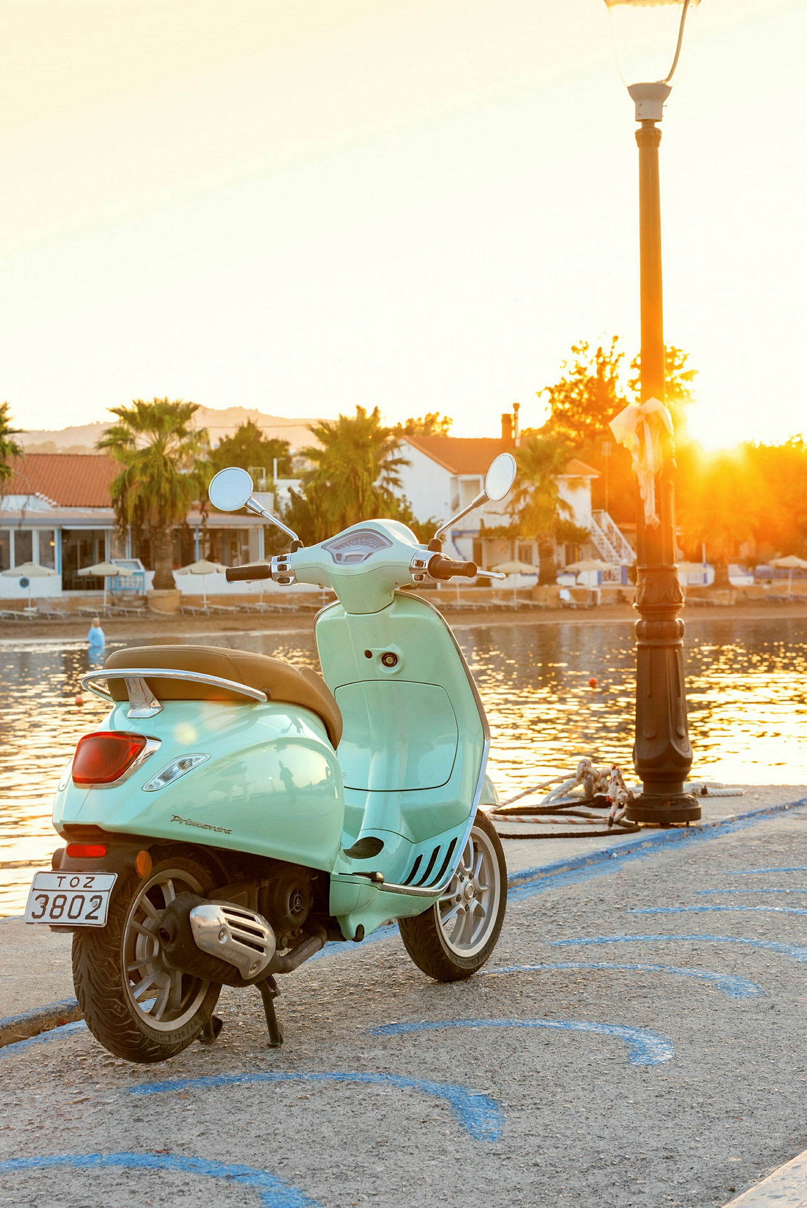 En ljusgrön scooter vid en kaj på kvällen med solen som går ned. (AI-genererad text)